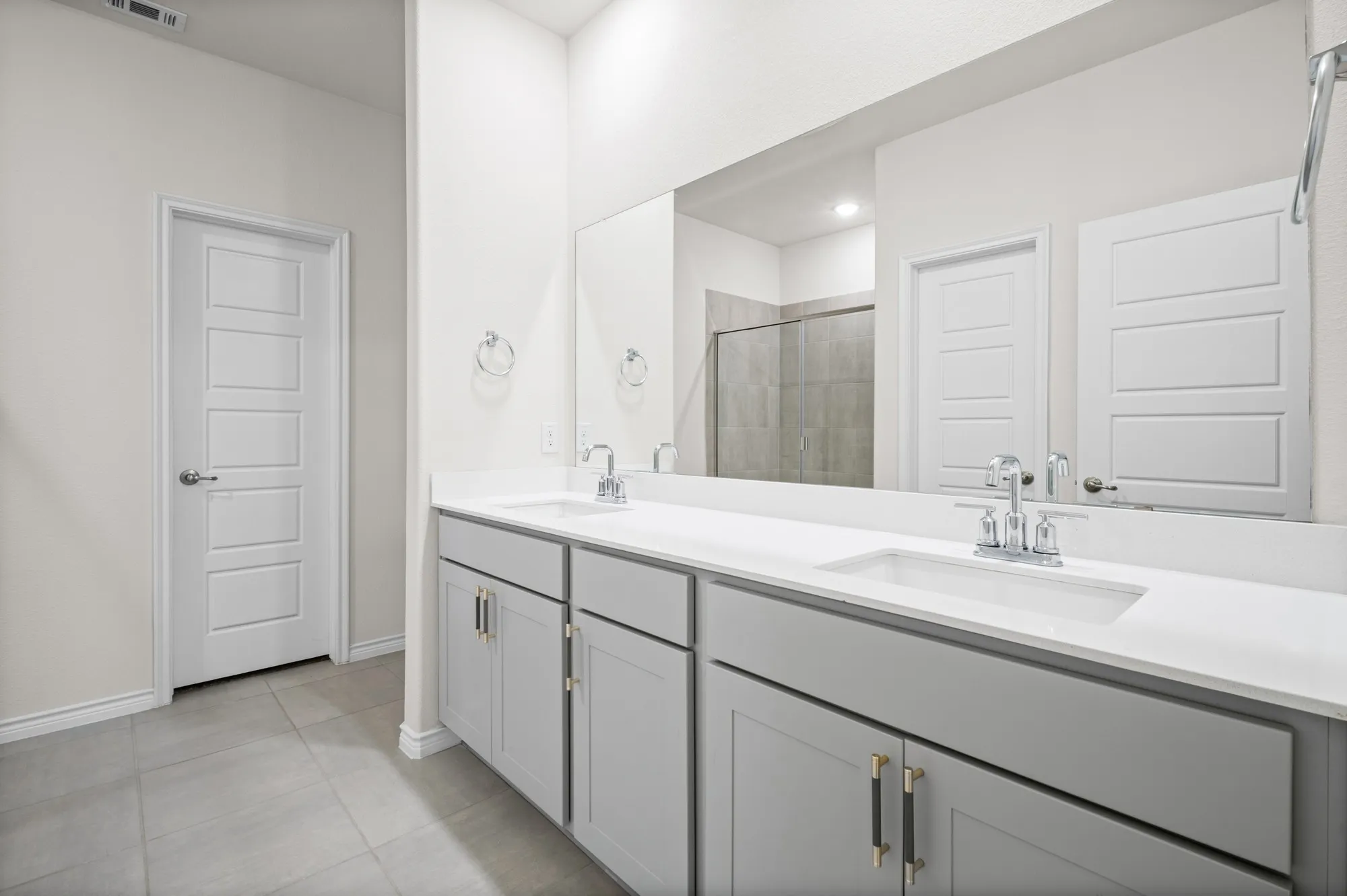 Dual vanity with light gray cabinetry, white countertops, and chrome fixtures