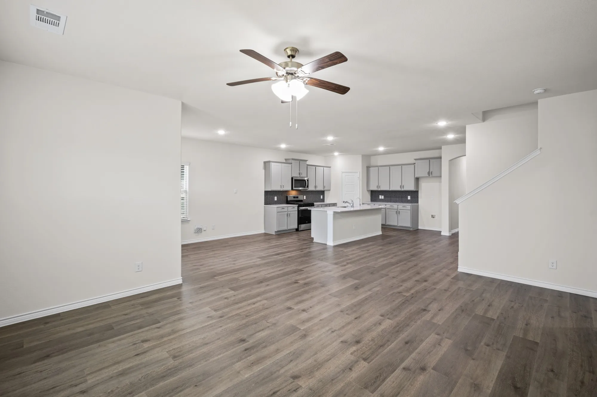 Open-concept living space with wood-finish flooring, recessed lighting, and a ceiling fan