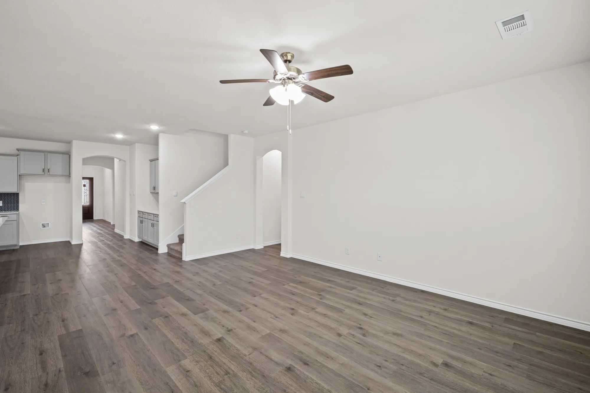 Spacious room featuring wood-finish flooring, recessed lighting, and a ceiling fan
