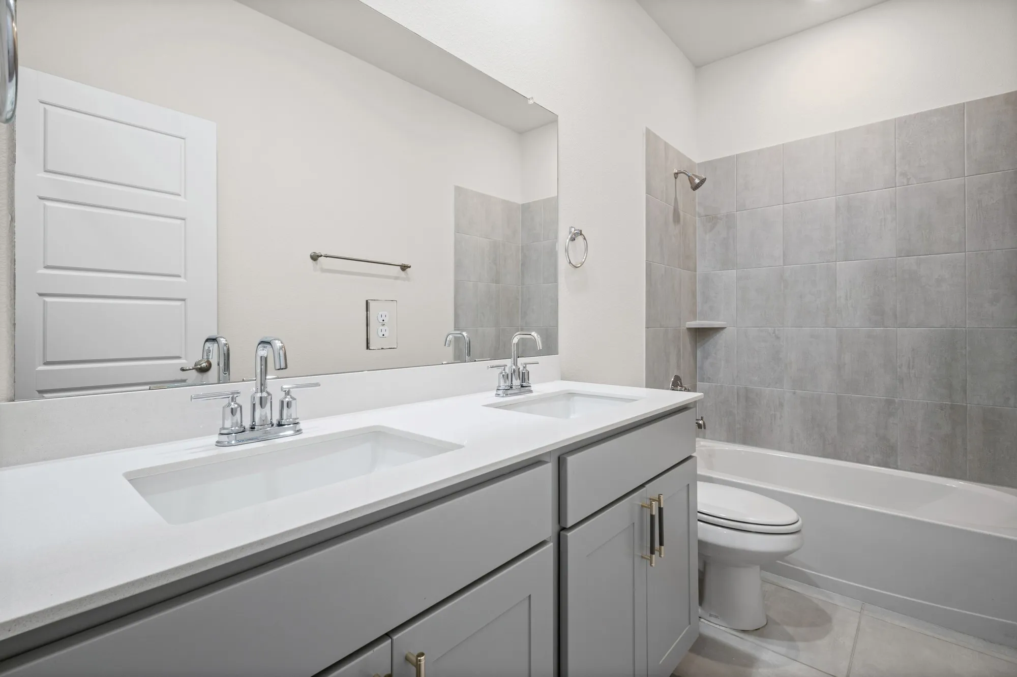 Double vanity with integrated sinks, light gray cabinetry, and chrome hardware
