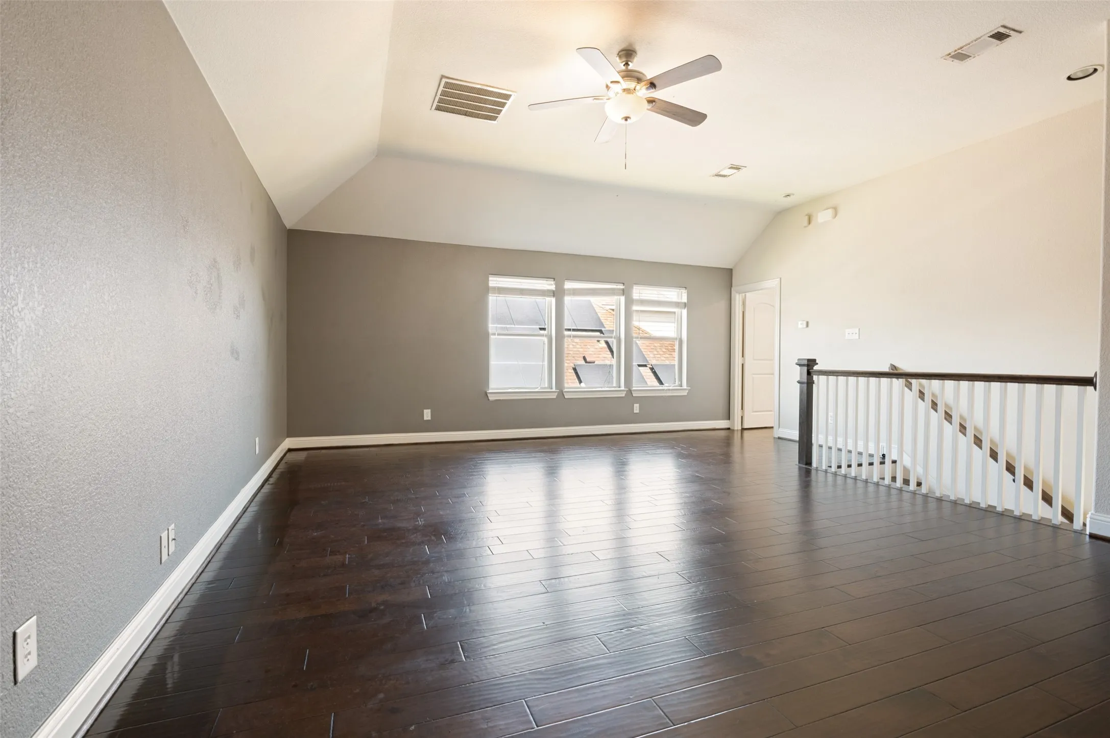 Vaulted ceiling featuring a ceiling fan, recessed lighting, wood-finish flooring, and a staircase with a wood handrail