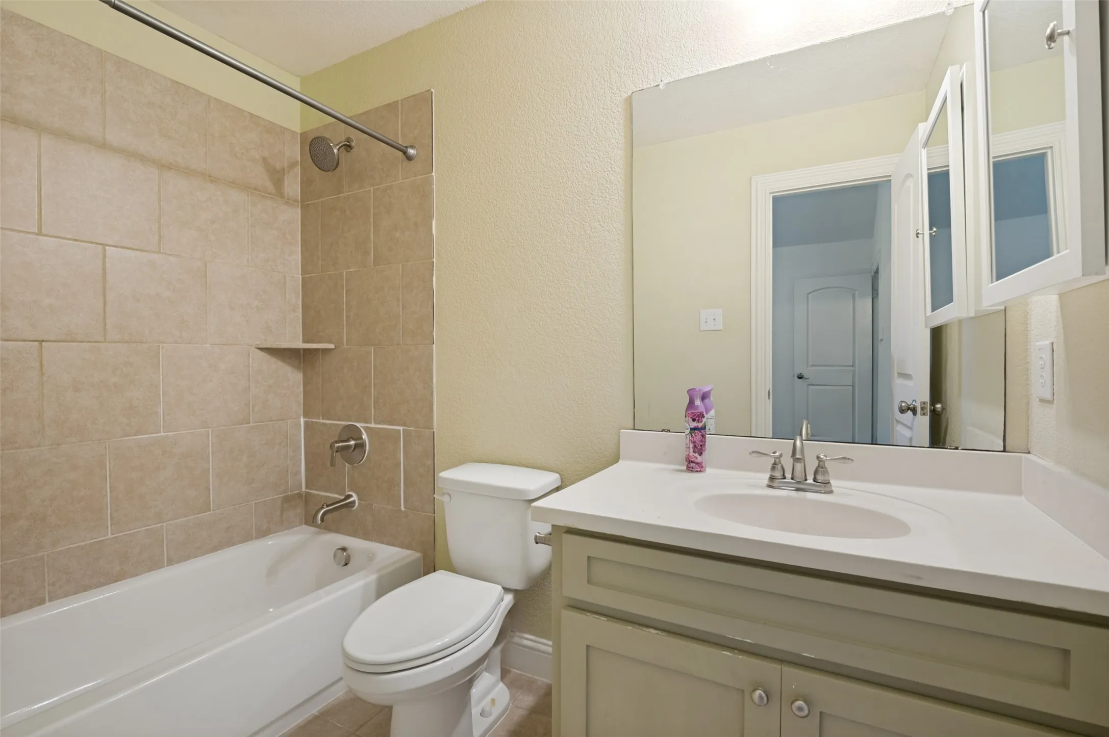 White bathtub with tiled surround, built-in shower niche, and brushed nickel fixtures