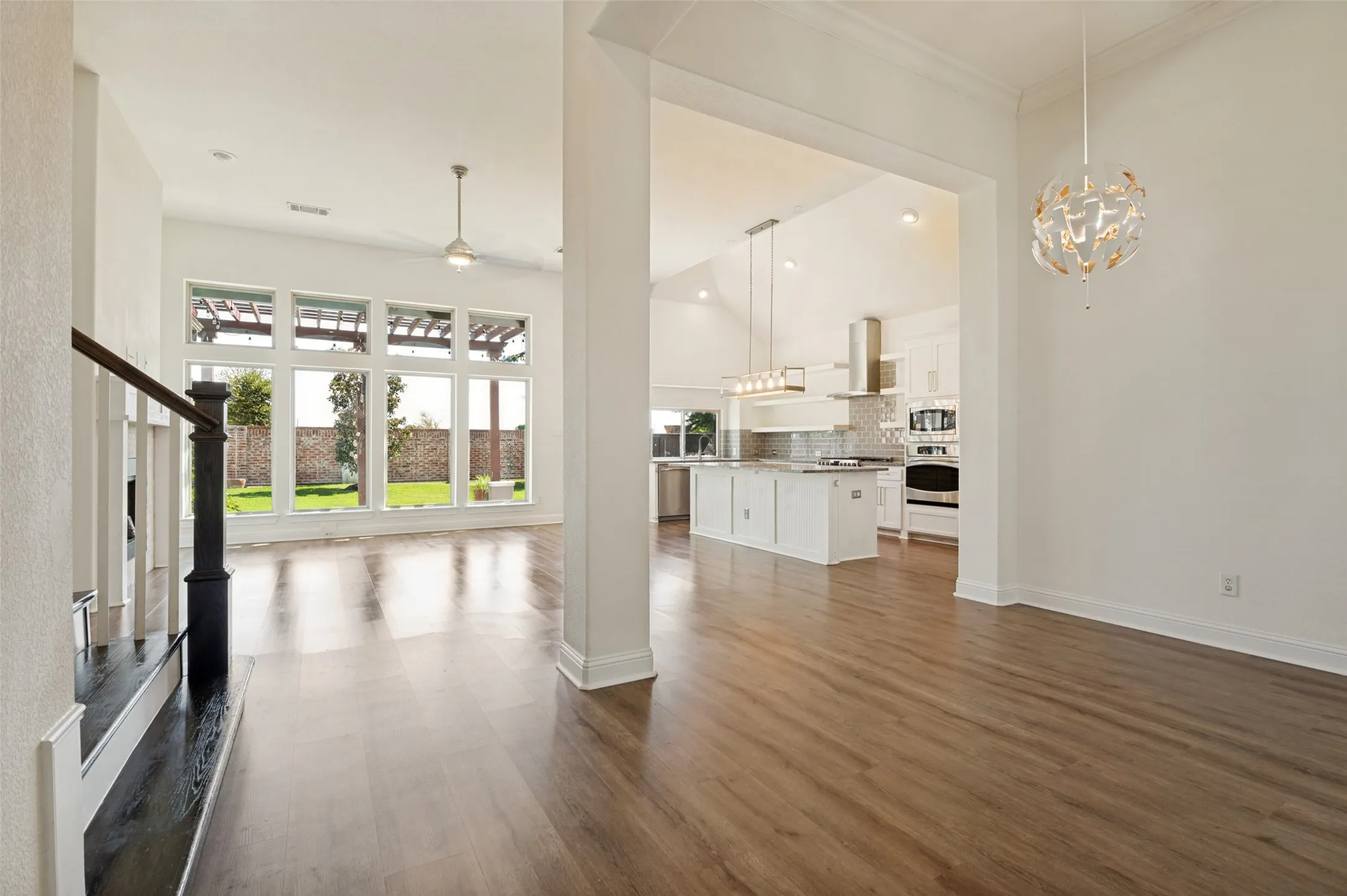 Open-concept interior featuring wood-finish flooring, high ceilings, and a modern kitchen with a center island
