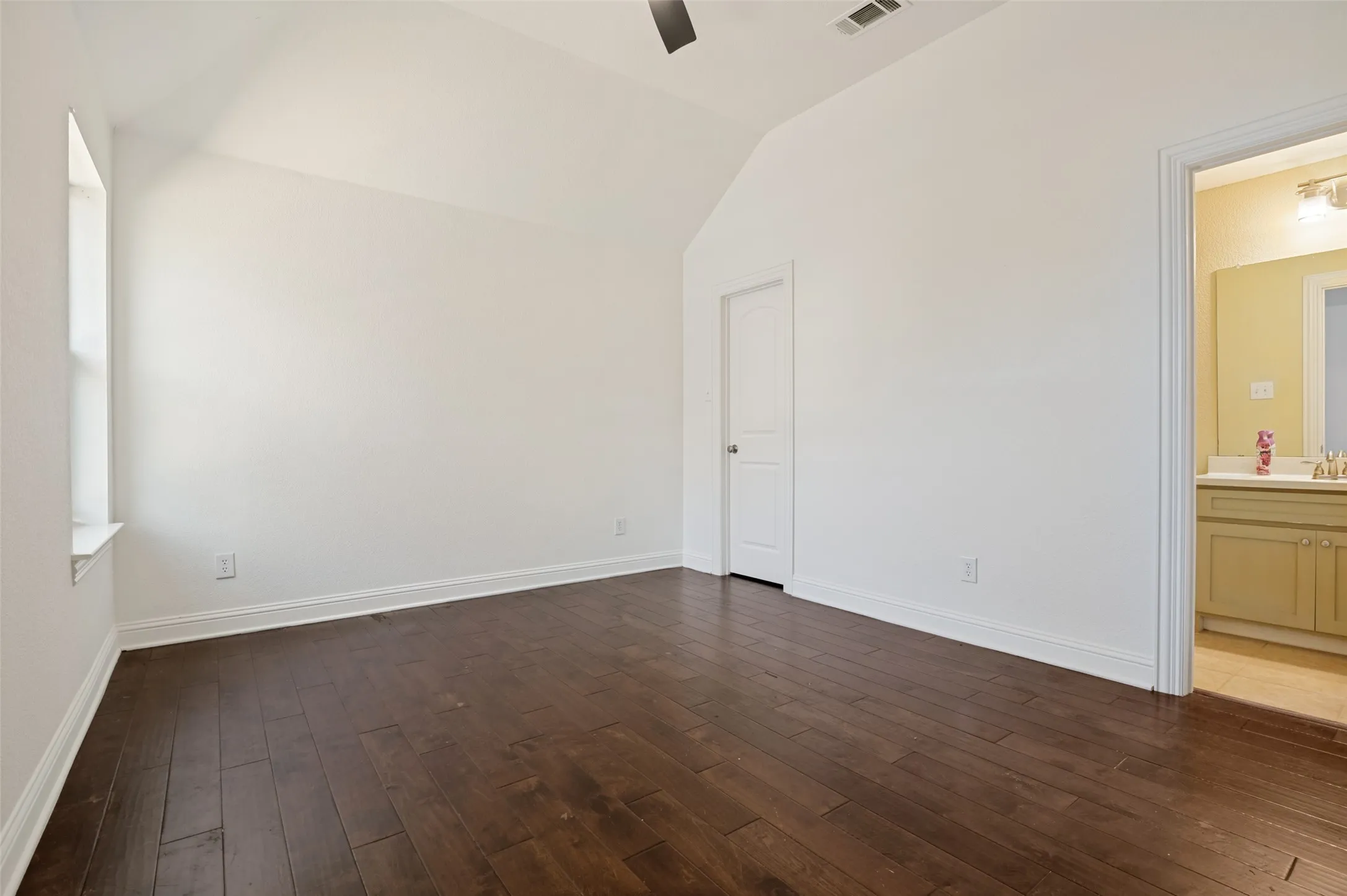 Vaulted ceiling with a ceiling fan, dark wood-finish flooring, white trim, and a window with a sill