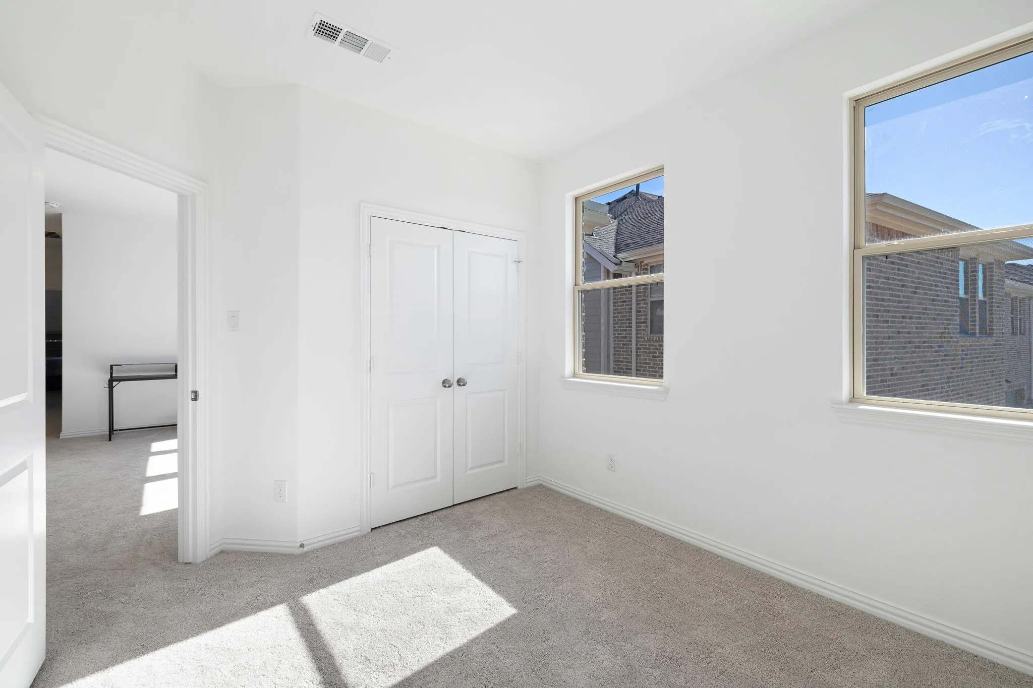 Neutral paint tones, carpeted flooring, two double-hung windows, and a bi-fold closet door