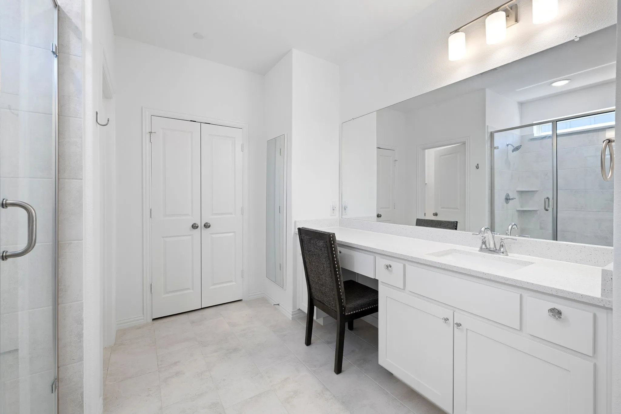 White vanity with a single basin sink and white countertop, full-width mirror, and track lighting
