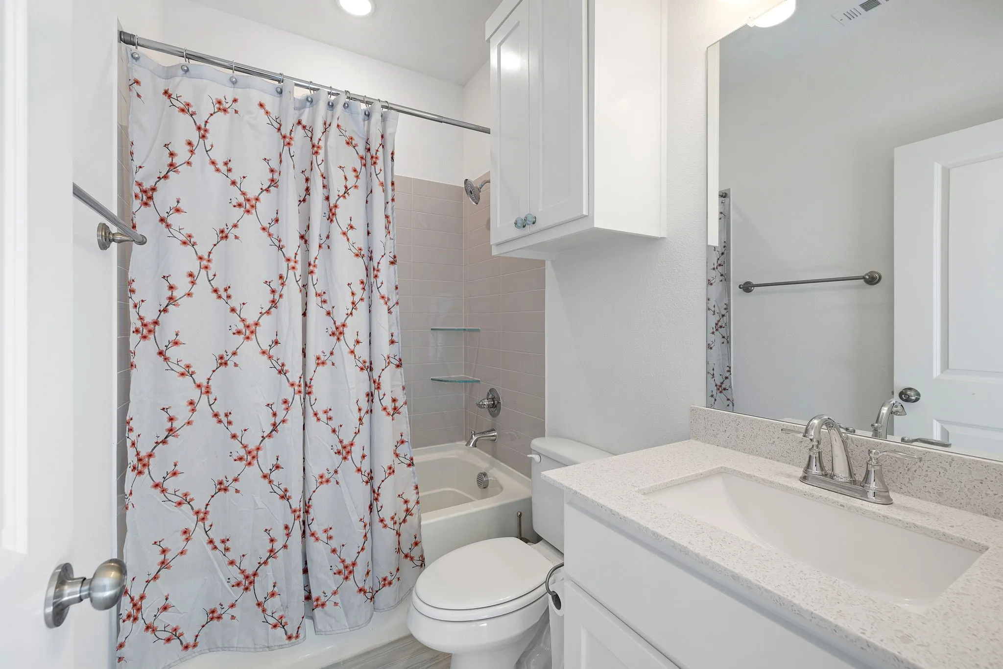 White vanity with integrated sink, brushed nickel faucet, and overhead cabinetry