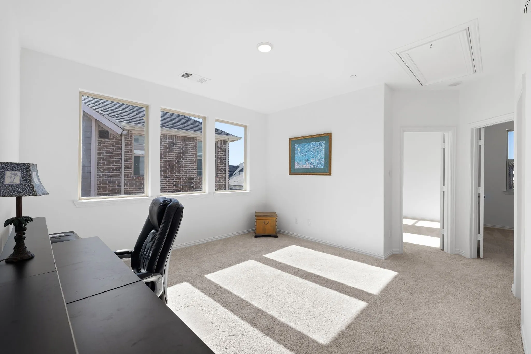 Light-colored carpet flooring, white walls, three rectangular windows, and recessed ceiling lighting