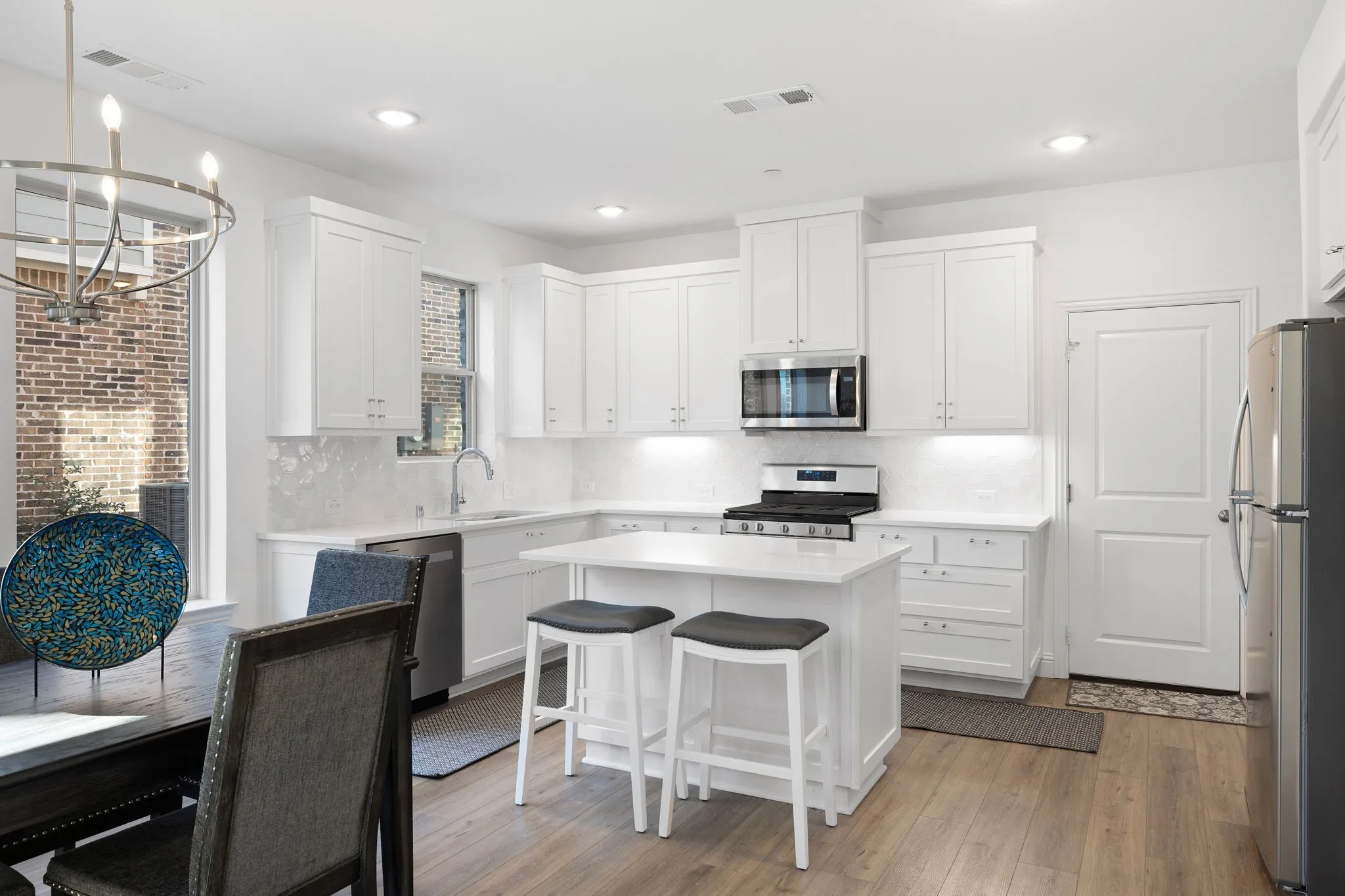 Kitchen featuring white cabinetry, stainless steel appliances, a center island, recessed lighting, and wood-finish flooring