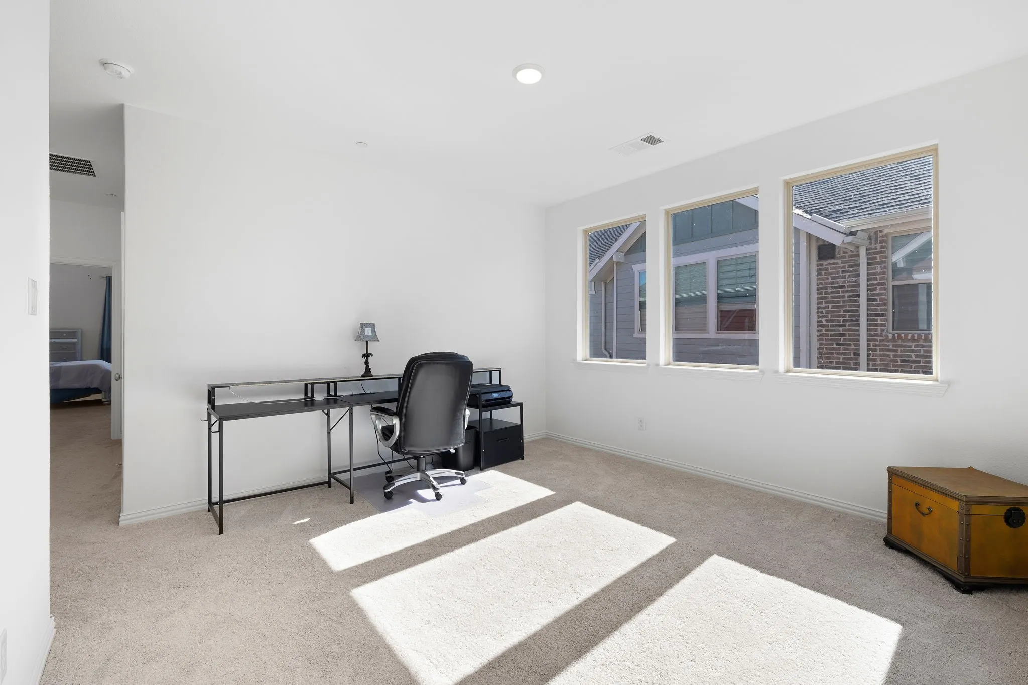 Recessed ceiling lighting, three prominent windows, and light-colored carpeting