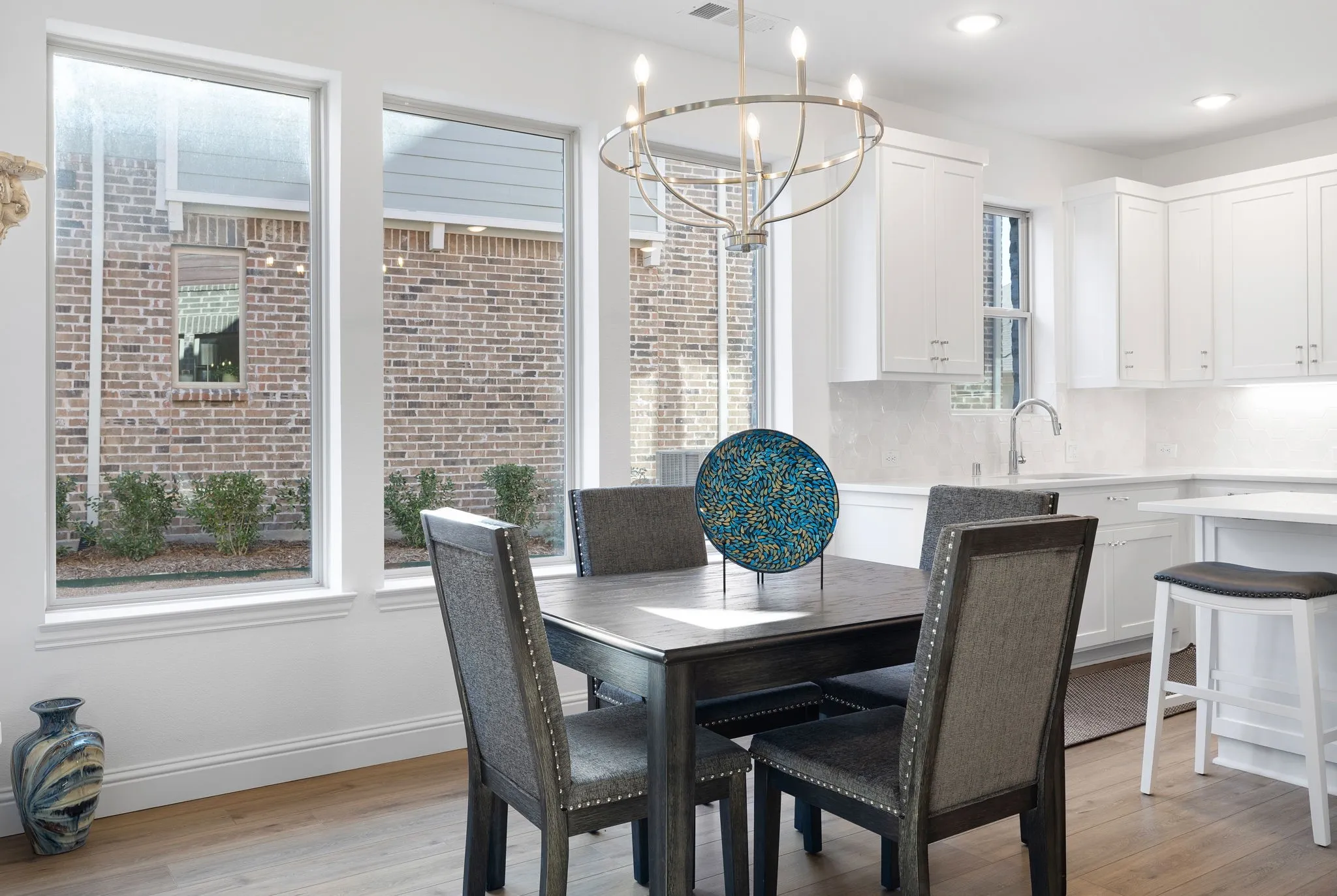 White shaker cabinetry, recessed lighting, wood-finish flooring, a contemporary chandelier, and large windows