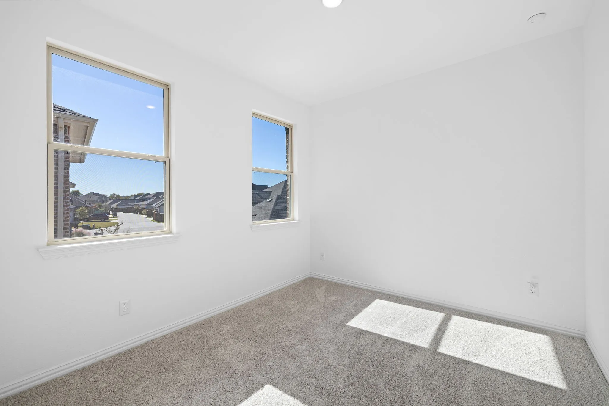 Neutral wall color with two double-hung windows, recessed ceiling lighting, and light-colored carpeting