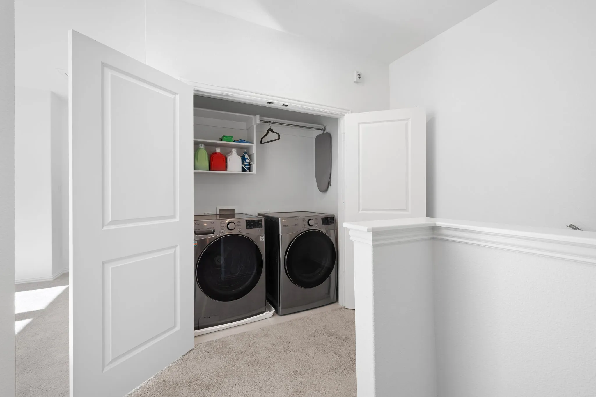 Convenient laundry closet featuring built-in shelving, a clothes hanging rod, and paneled doors