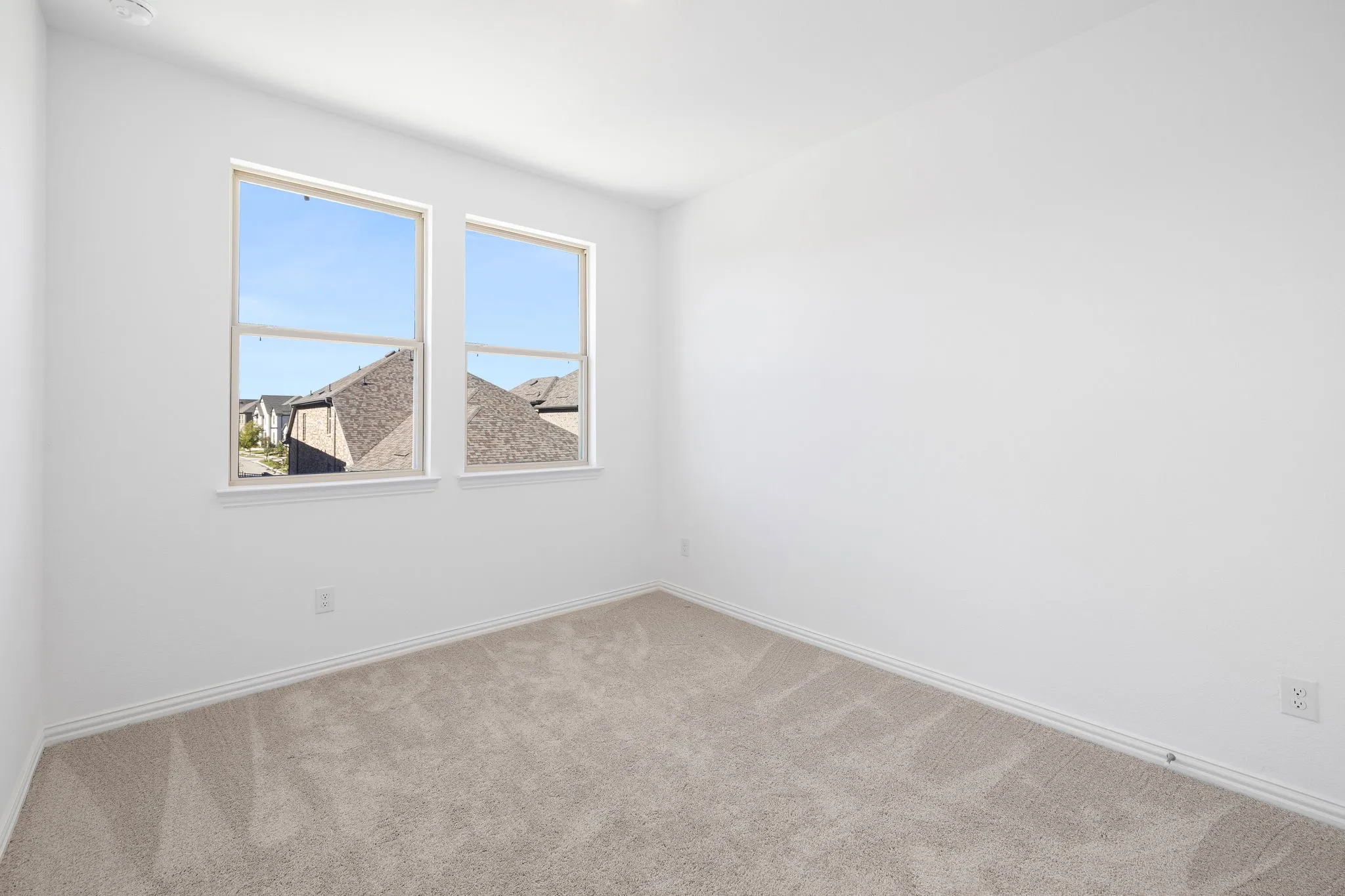 Neutral-toned carpeting, white walls, and two windows allowing natural illumination