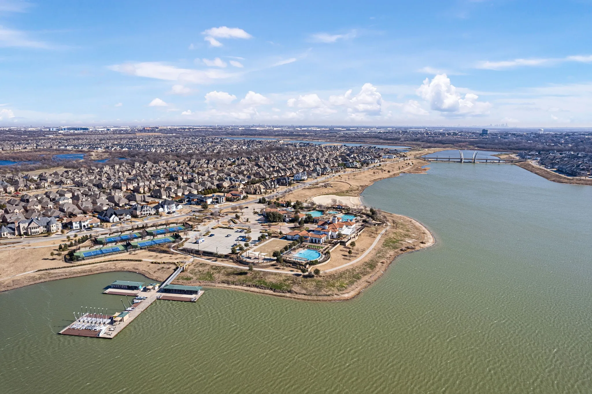 Waterfront community with extensive residential development, a community clubhouse, multiple swimming pools, tennis courts, and a marina with boat slips