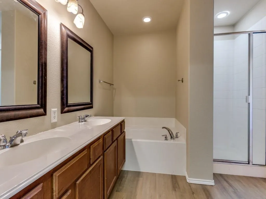 Dual vanity with integrated sinks, framed mirrors, and a separate soaking tub