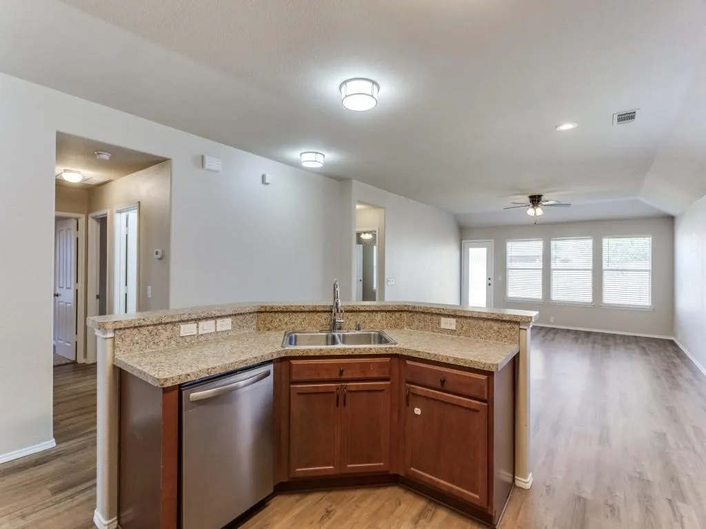 Kitchen island with granite-finish countertop, stainless steel sink, and wood cabinetry