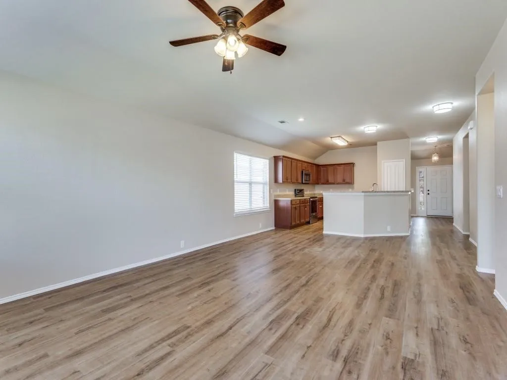 Expansive living area with wood-finish flooring, recessed lighting, and a ceiling fan