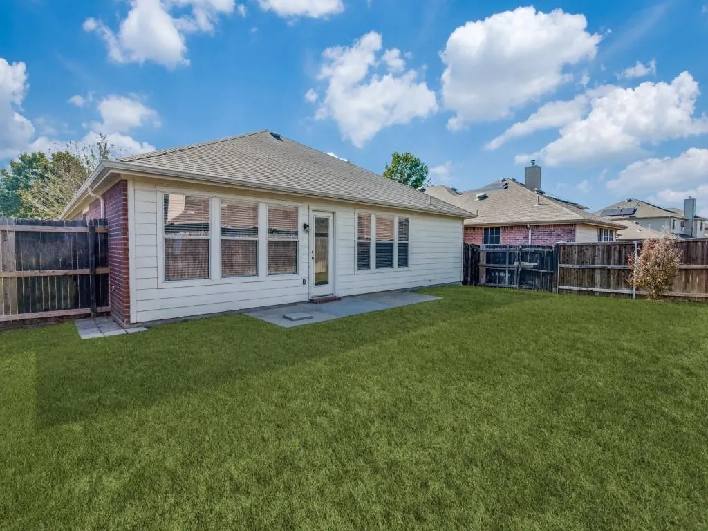 Expansive backyard with a manicured lawn, full fencing, and a concrete patio