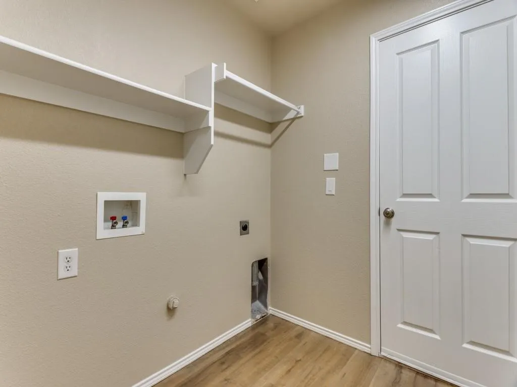 Laundry area featuring wood-finish flooring and built-in shelving