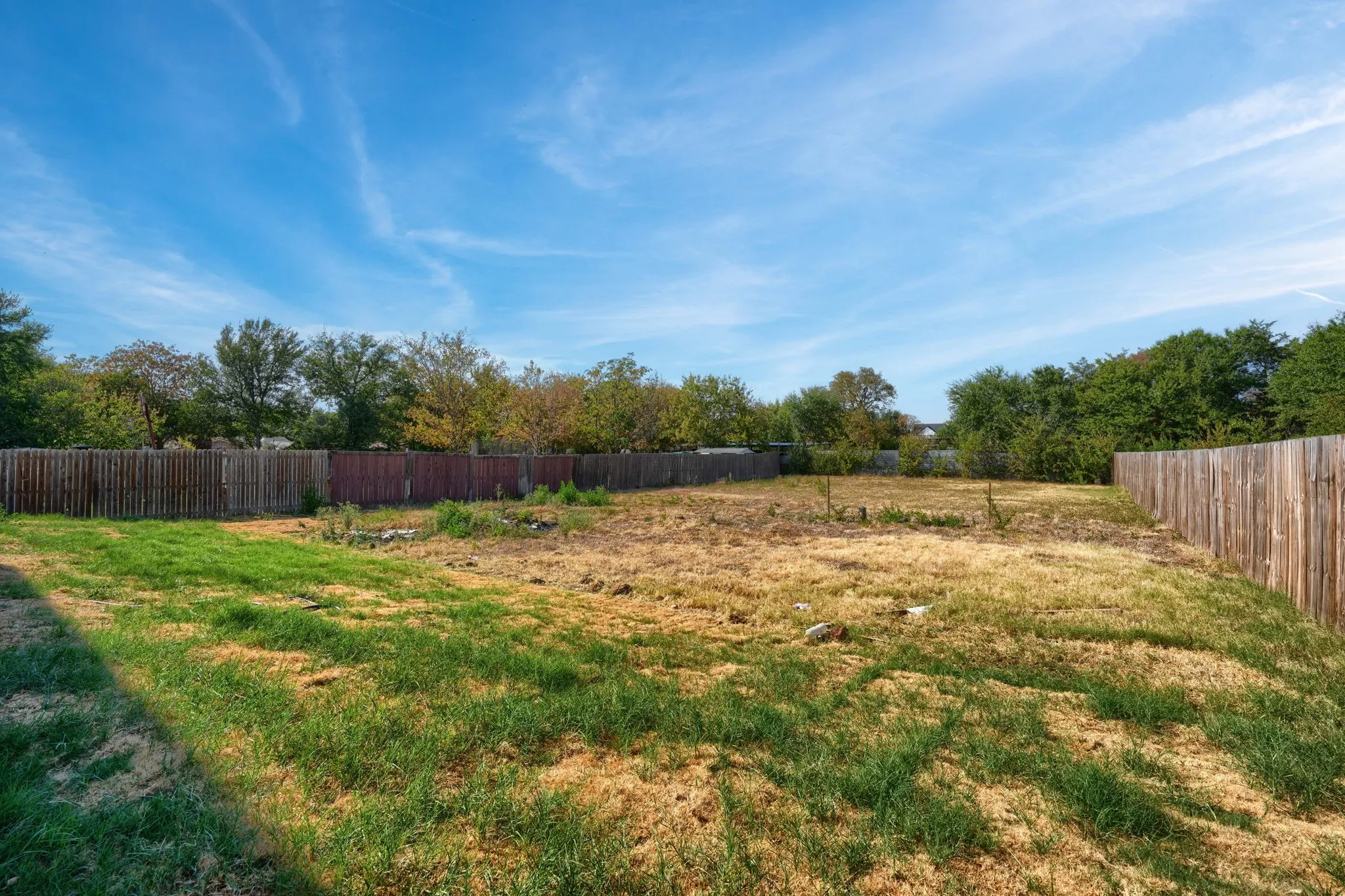 Expansive yard space featuring a partial wood privacy fence