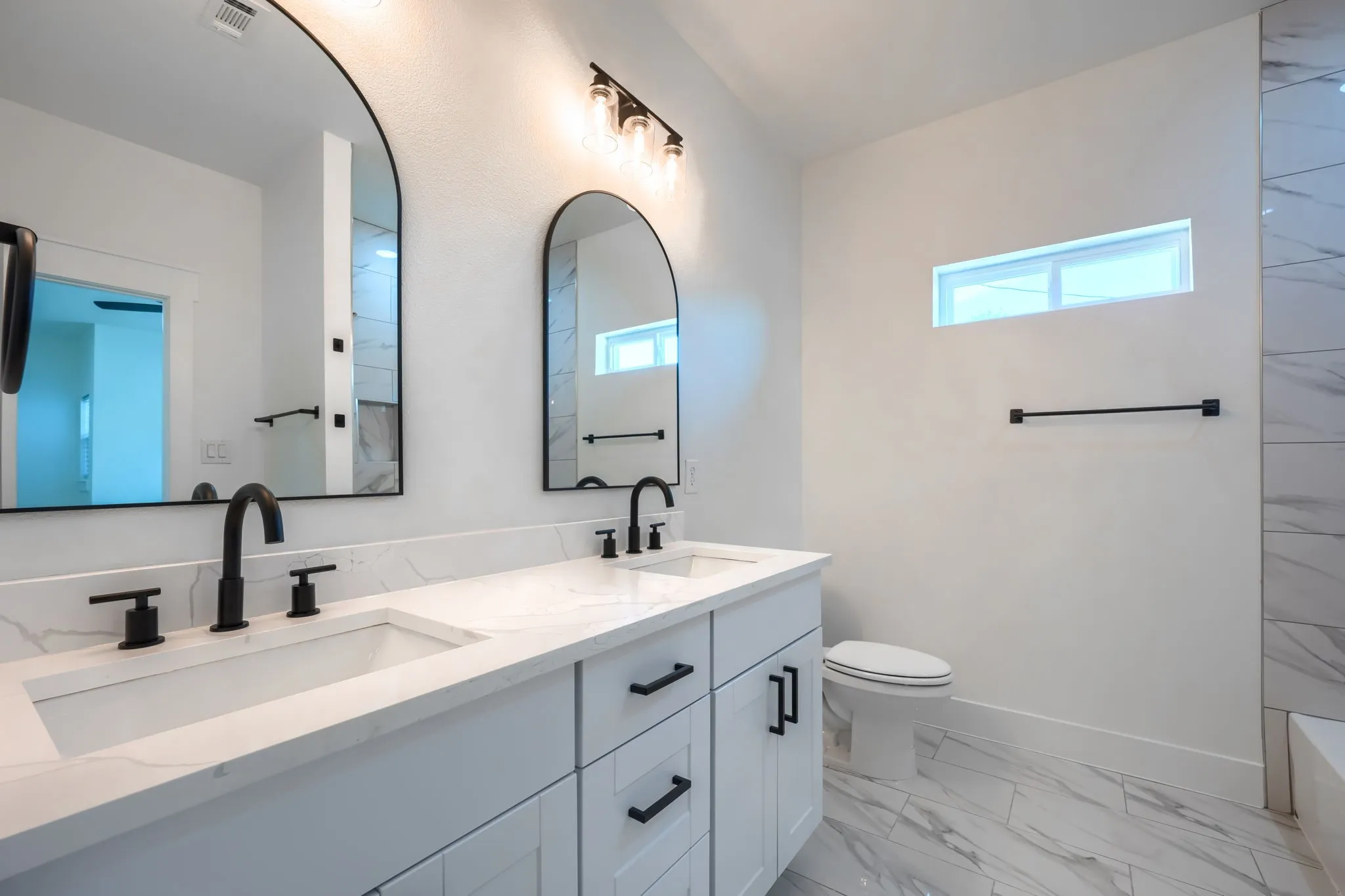 Dual vanity with white cabinetry and integrated sinks, complemented by matte black fixtures