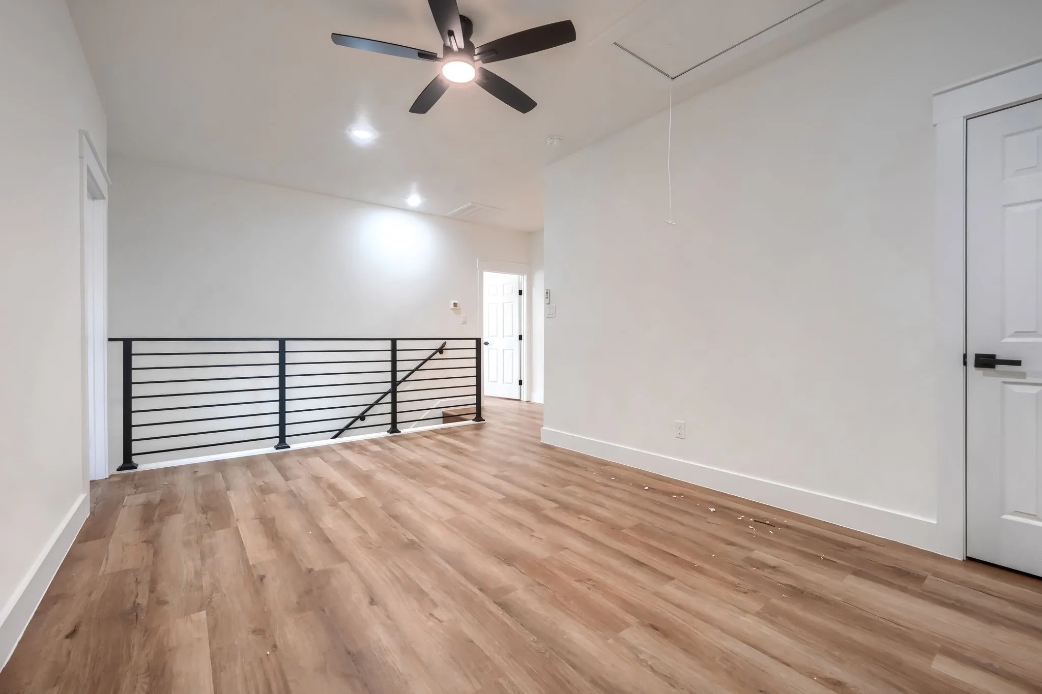 Wood-finish flooring throughout, complemented by a contemporary black metal horizontal railing
