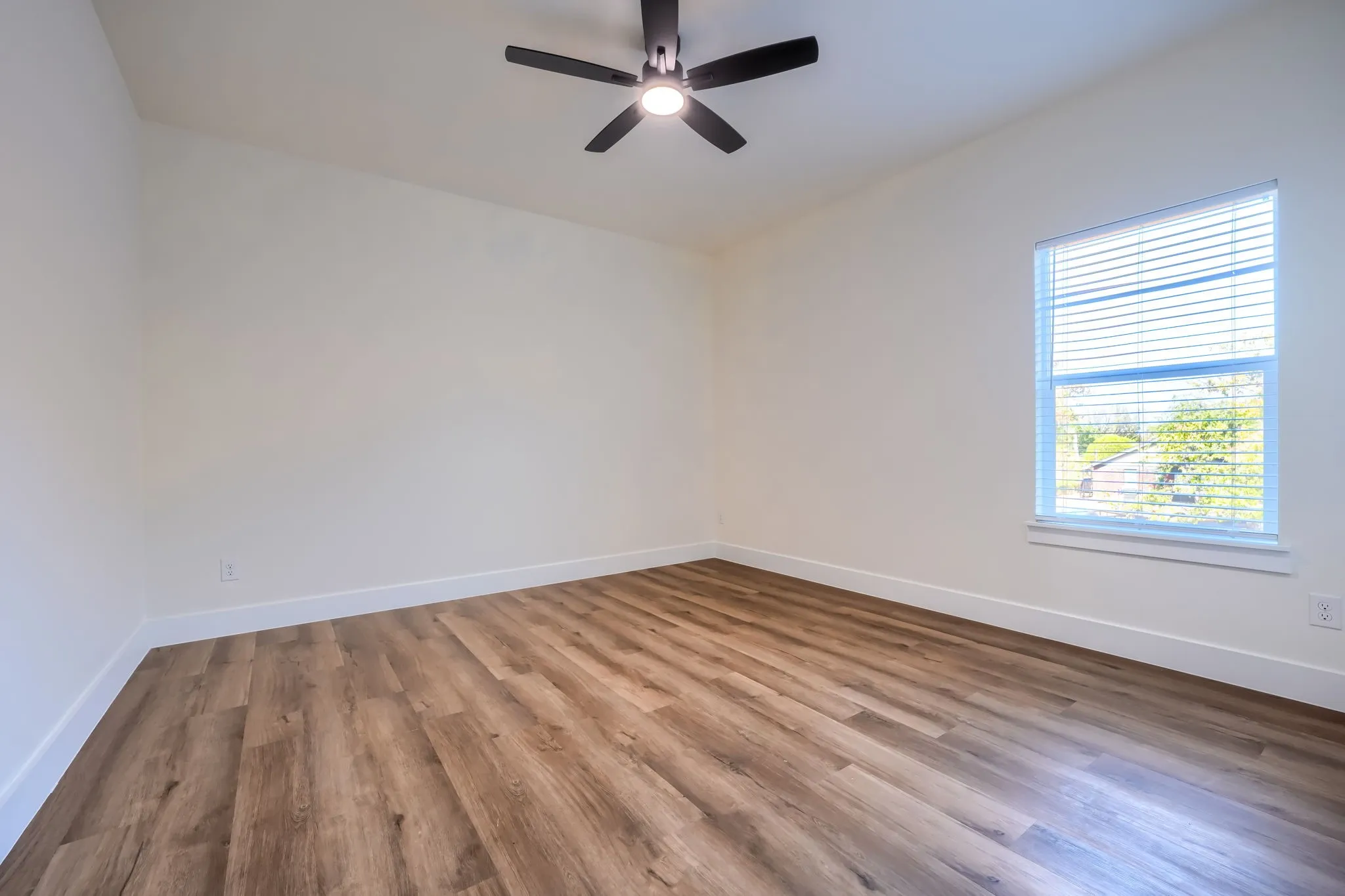 Neutral wall paint, wood-finish flooring, ceiling fan with integrated lighting, and window with blinds