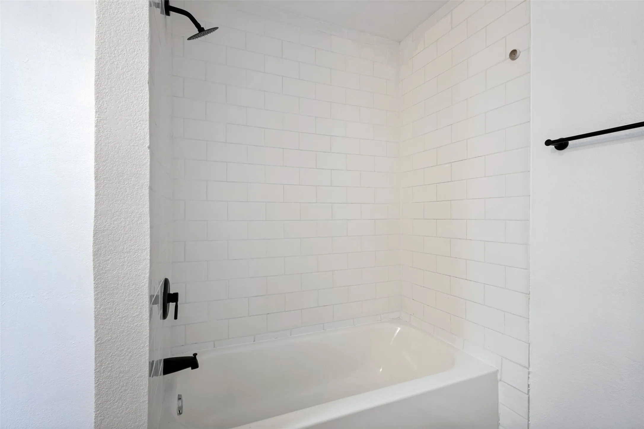White subway tile surround with matte black fixtures and a built-in bathtub