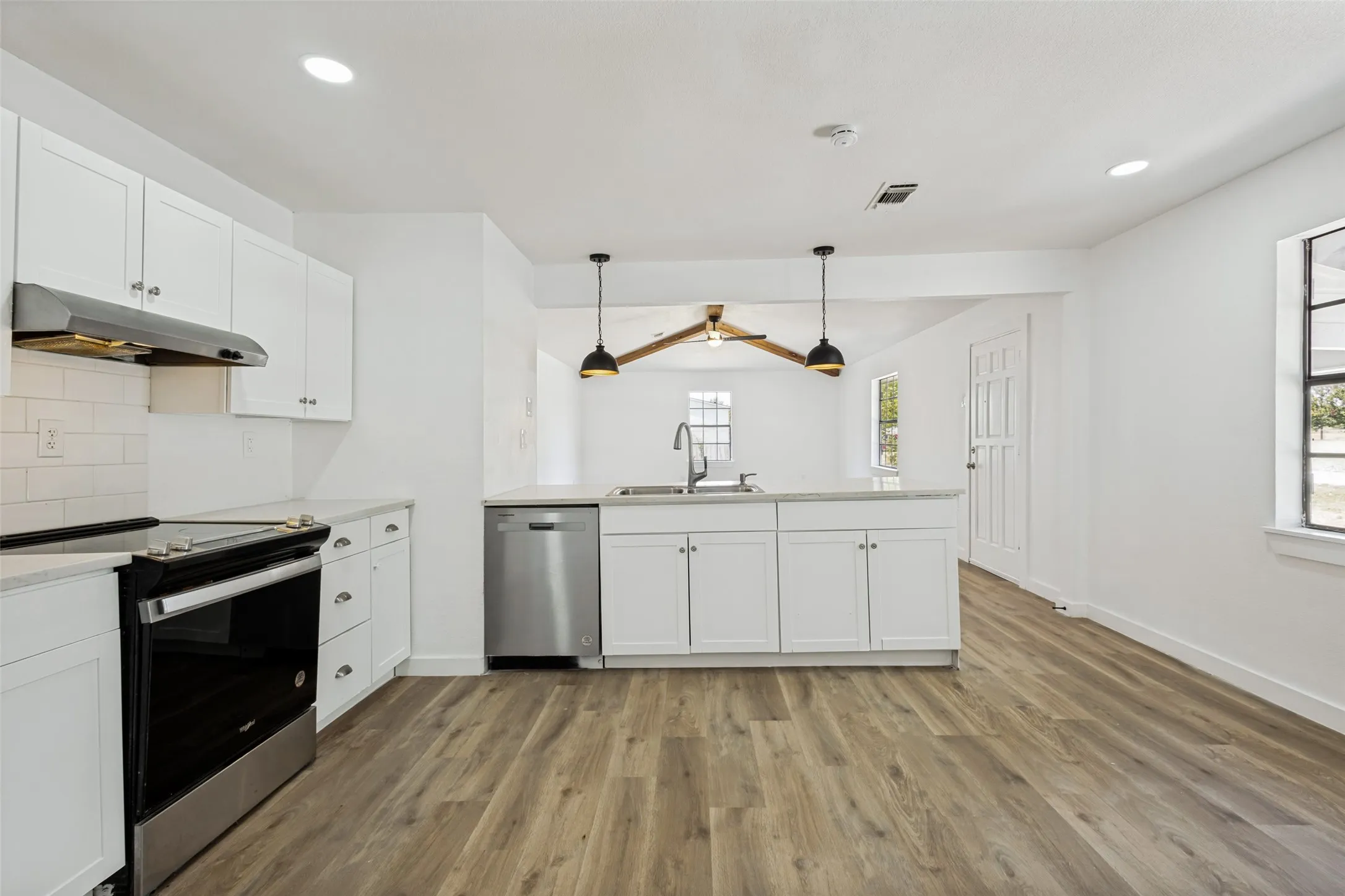 Kitchen featuring white shaker cabinetry, stainless steel appliances, wood-finish flooring, recessed lighting, and an island with pendant lighting