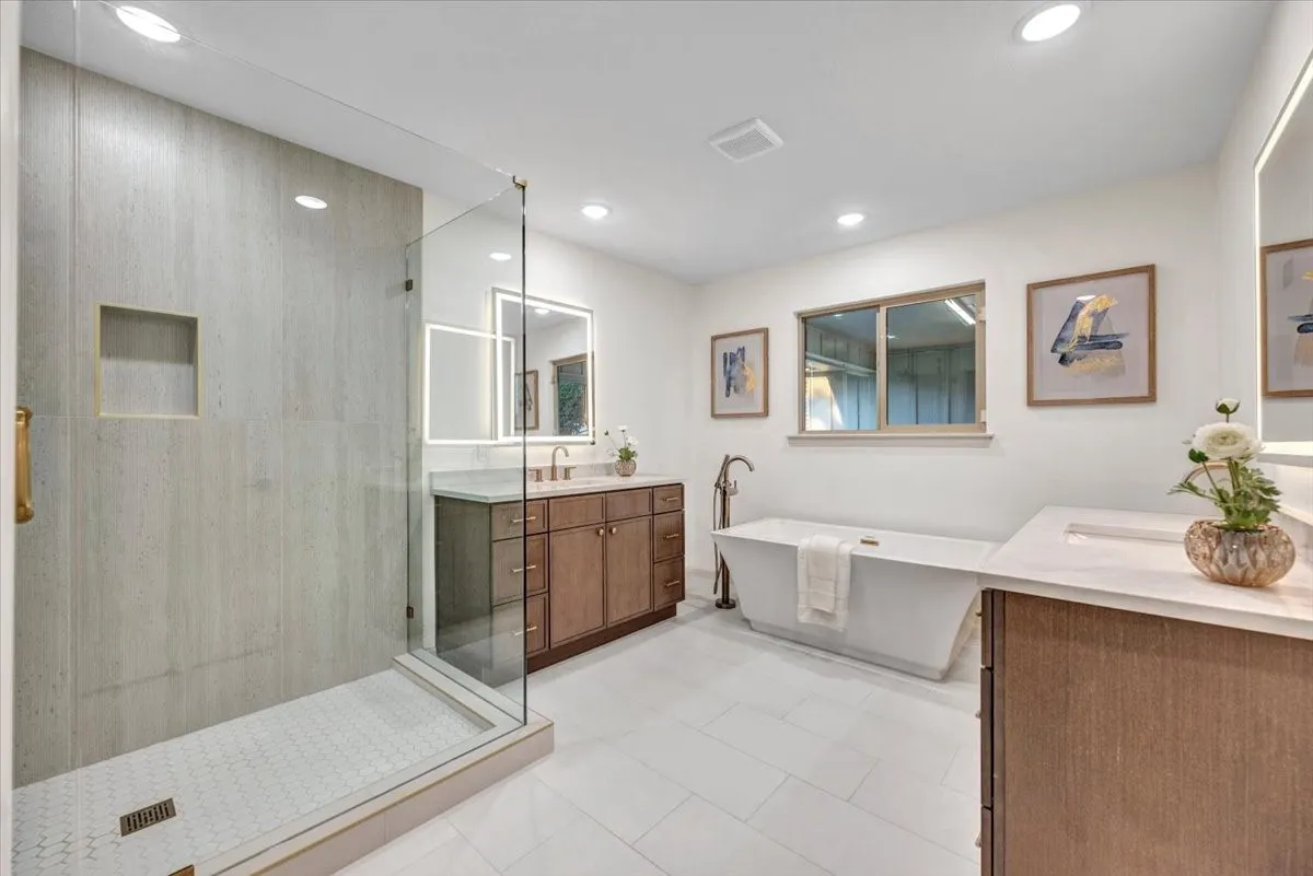 Completely reimagined primary bathroom with double vanities, stand alone tub and large shower