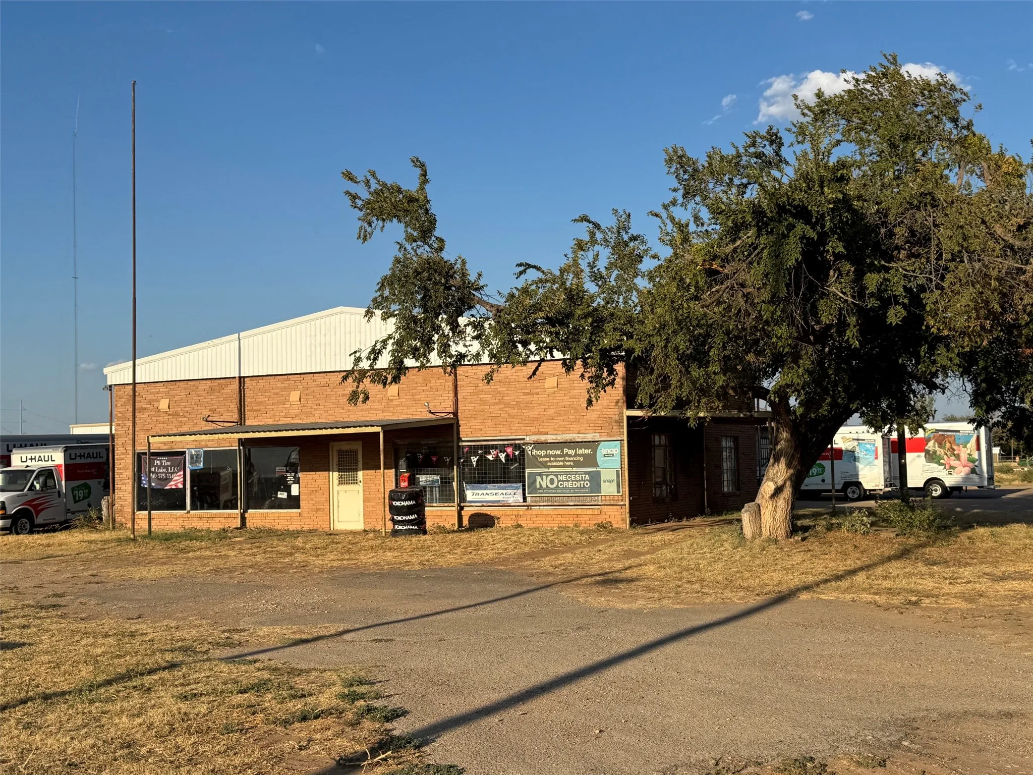 Brick exterior commercial building with a light-colored roofline and multiple window displays
