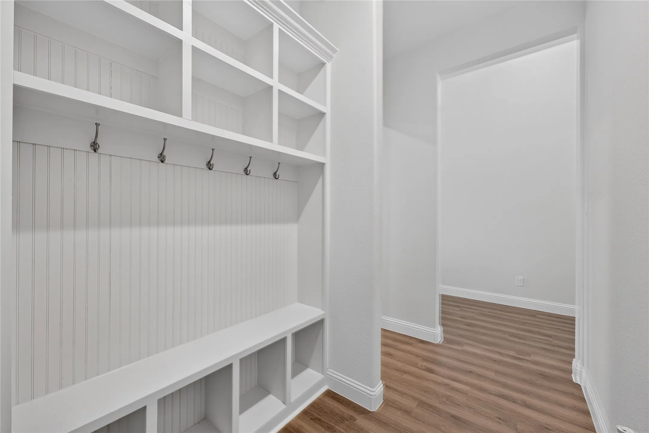 Built-in storage unit with upper shelving, coat hooks, and lower cubbies