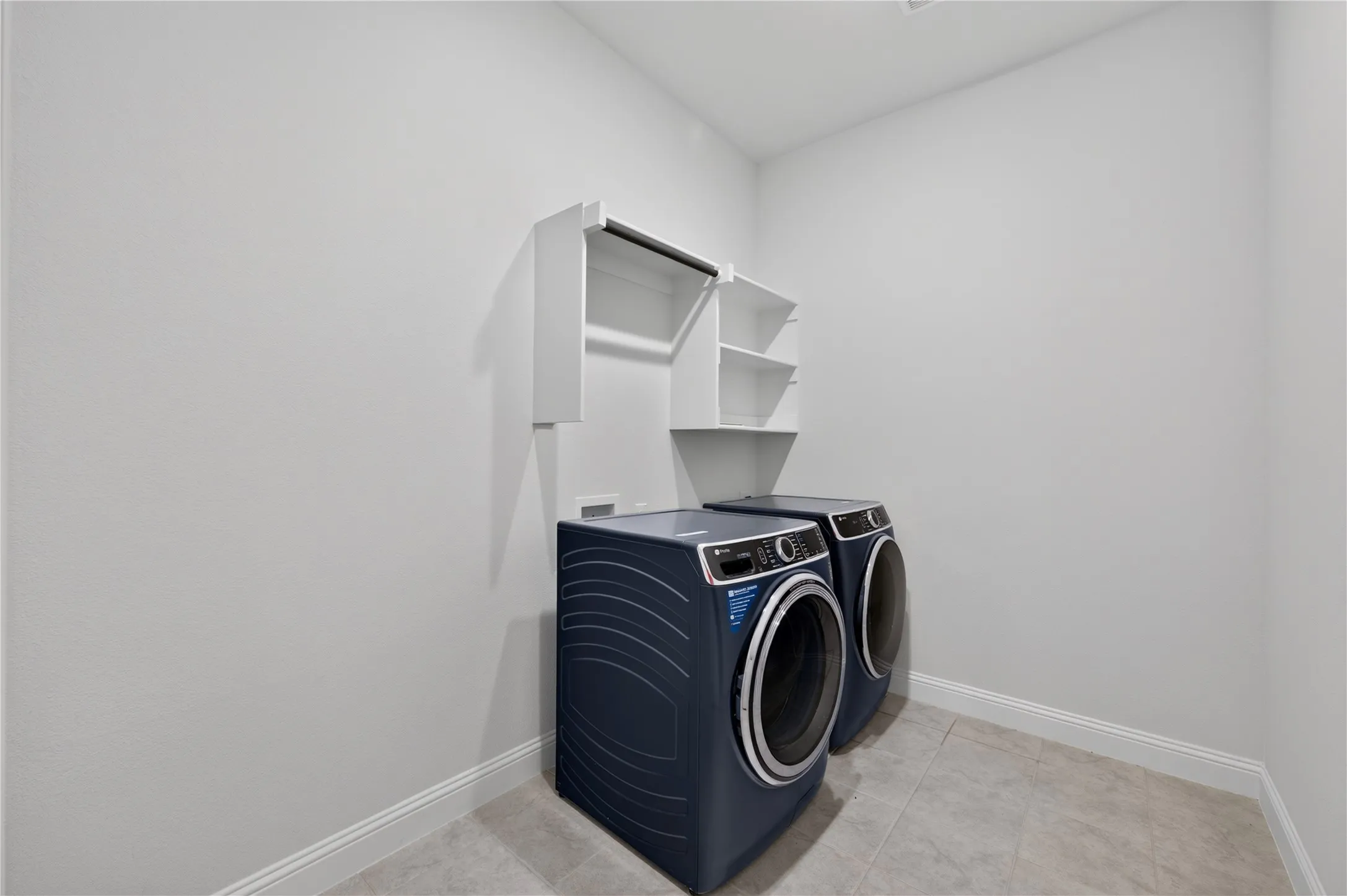 Laundry area with tile flooring and built-in shelving
