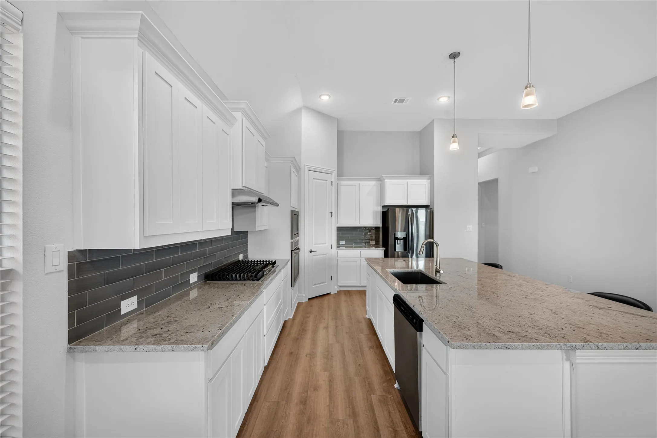 Kitchen featuring a gas range, white cabinetry, dark tile backsplash, and light-colored countertops with a stainless steel sink