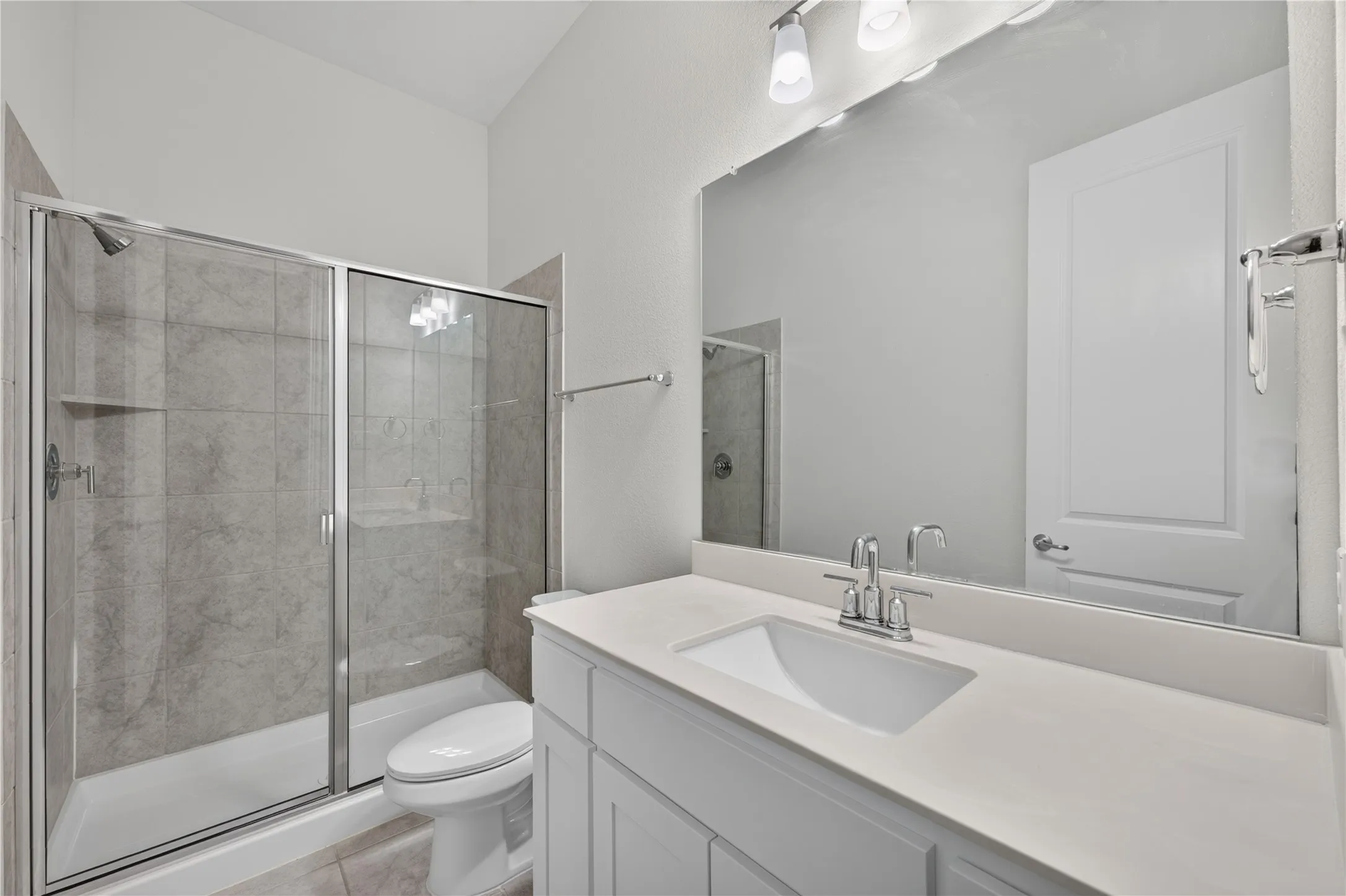 Full shower enclosure with sliding glass doors, a vanity with a rectangular undermount sink, a large wall-mounted mirror, and wall-mounted light fixtures