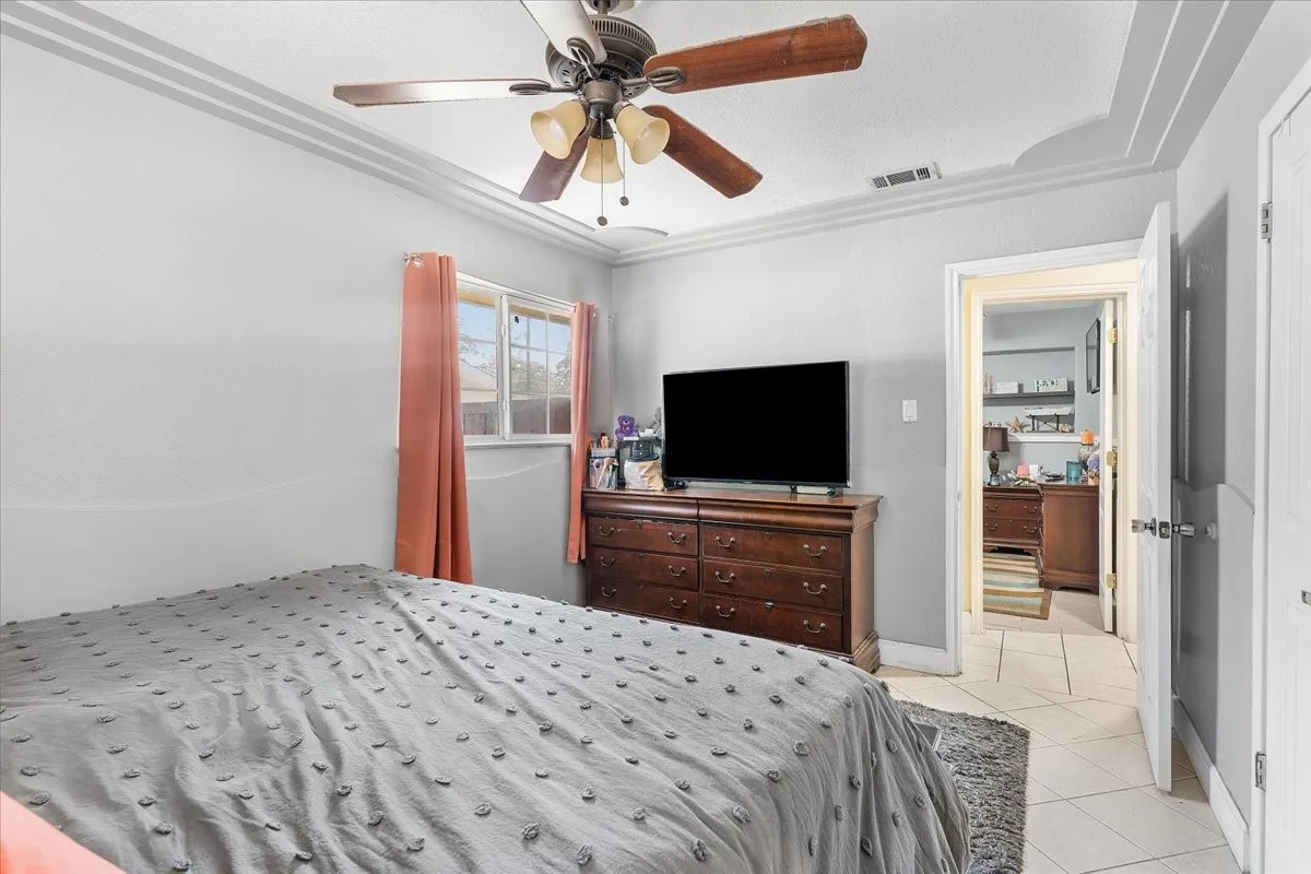 Original Photo -Bedroom 3 Ceiling fan with light kit, crown molding, double-pane window, tile flooring, and solid core interior door
