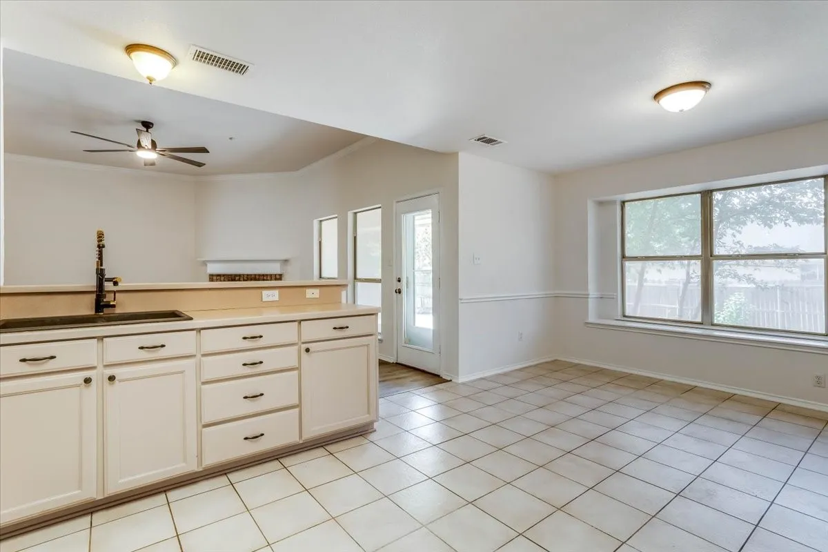 Kitchen with a breakfast bar, white cabinetry, dark sink, and a ceiling fan