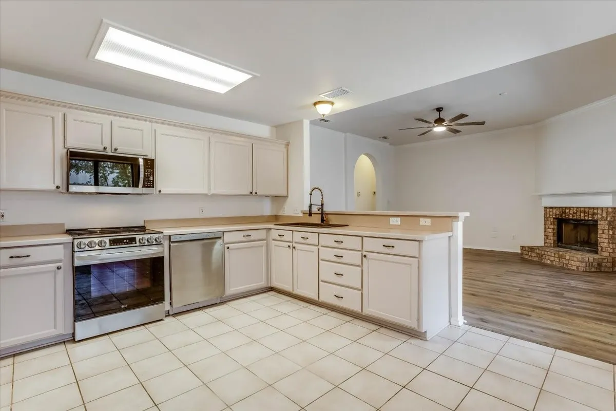 Kitchen featuring white cabinetry, stainless steel appliances, a bar-height counter, and tile flooring