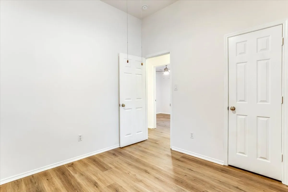 Wood-finish flooring, white paneled doors, vaulted ceiling, and neutral wall tones