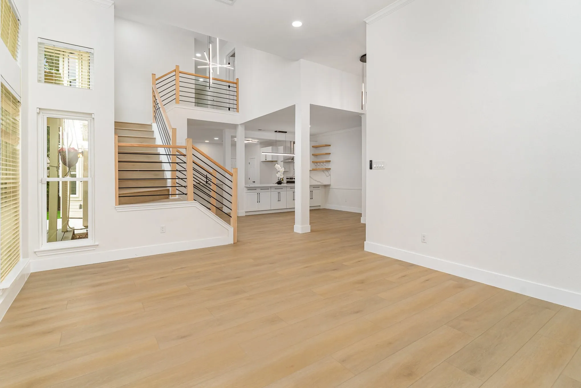 Unfurnished living room with a wealth of natural light, a high ceiling, and light wood-type flooring