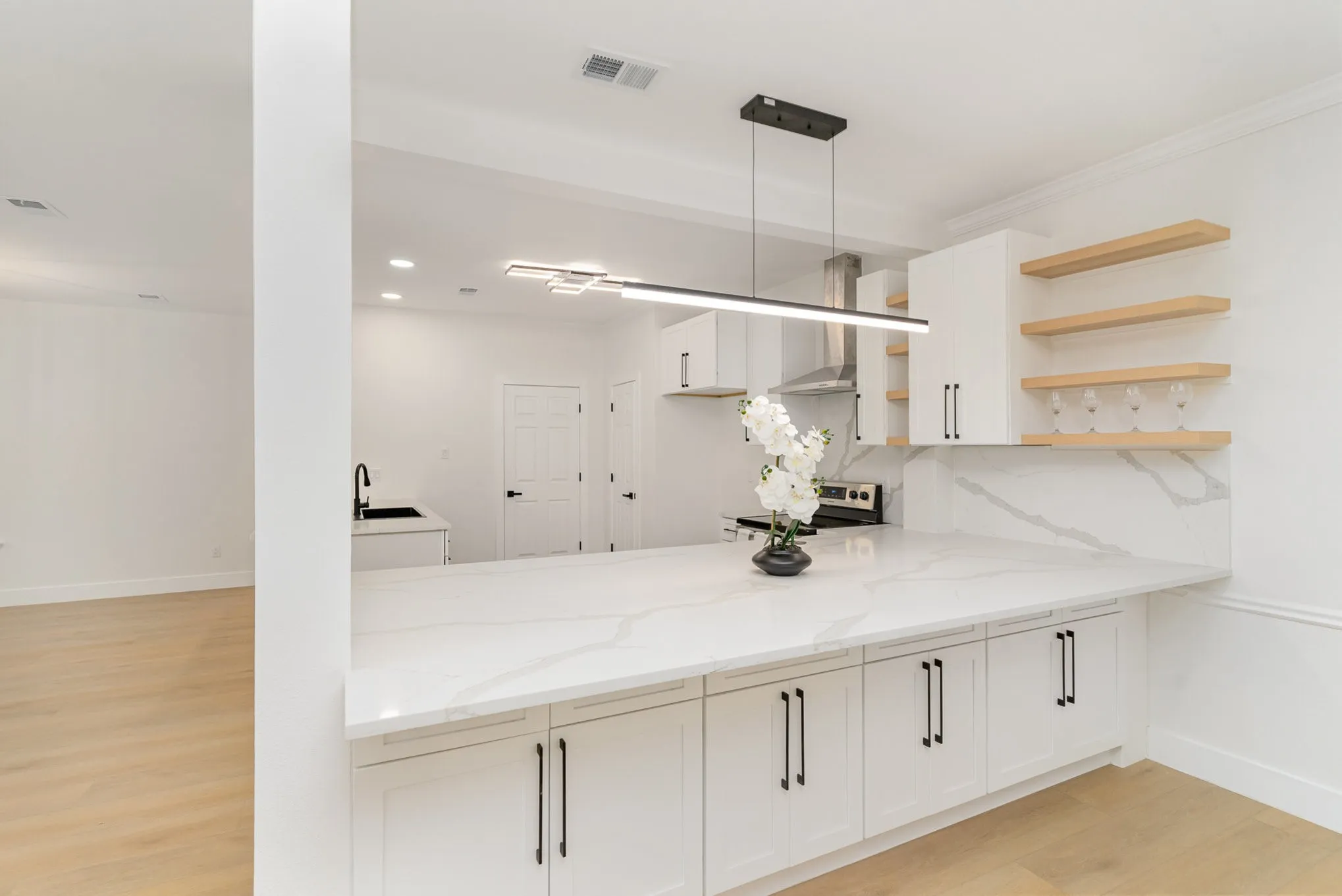 Kitchen with light stone counters, white cabinets, stainless steel electric stove, pendant lighting, and light wood-type flooring
