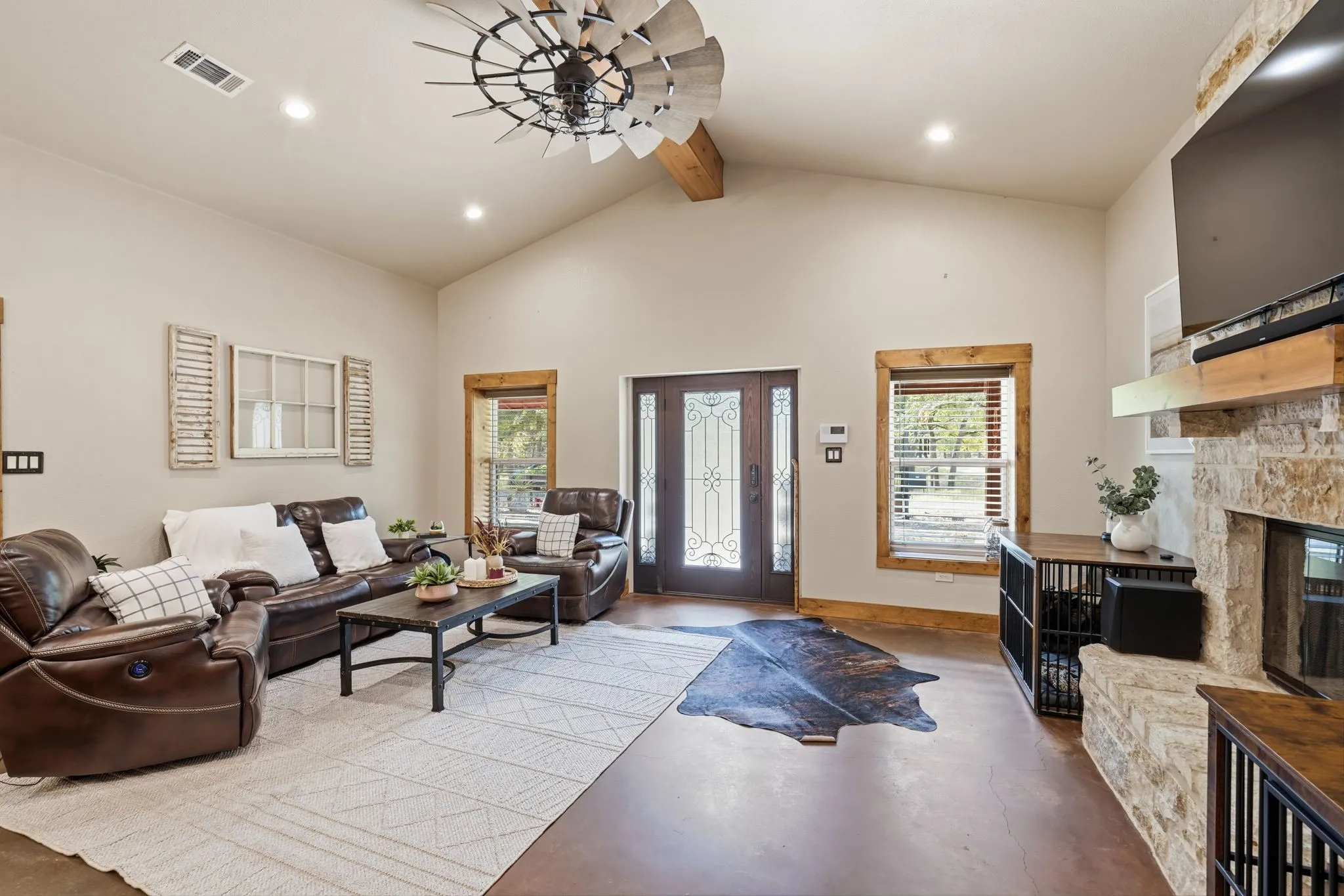 Vaulted ceilings with exposed wood beam, recessed lighting, windmill-style ceiling fan, and stained concrete flooring