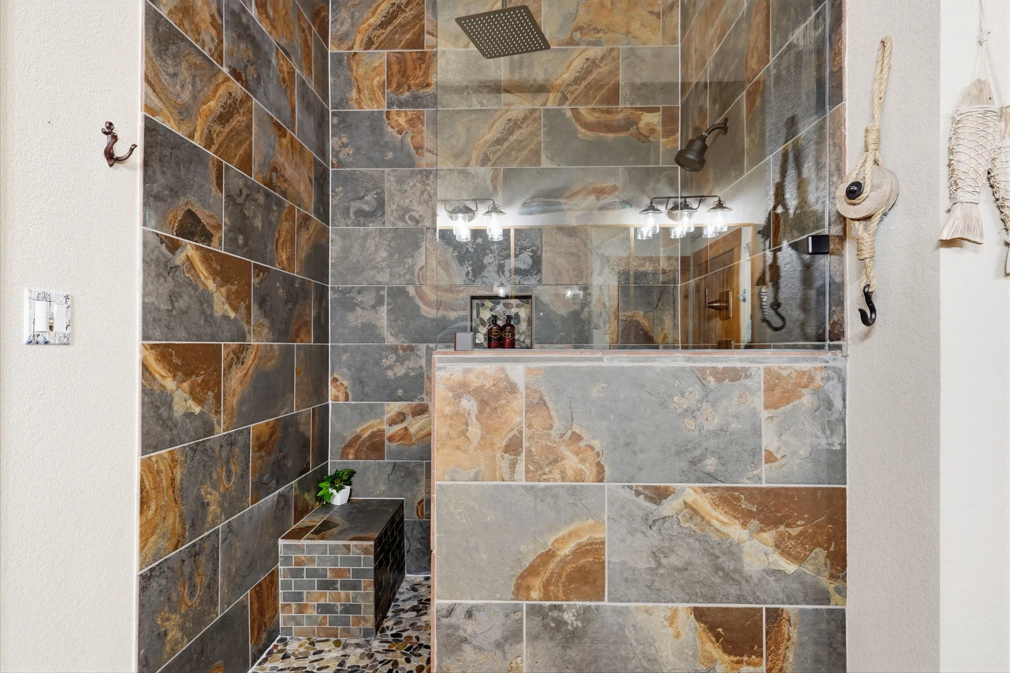 Floor-to-ceiling slate tile shower with a built-in bench, rainfall showerhead, and pebble-finish shower floor