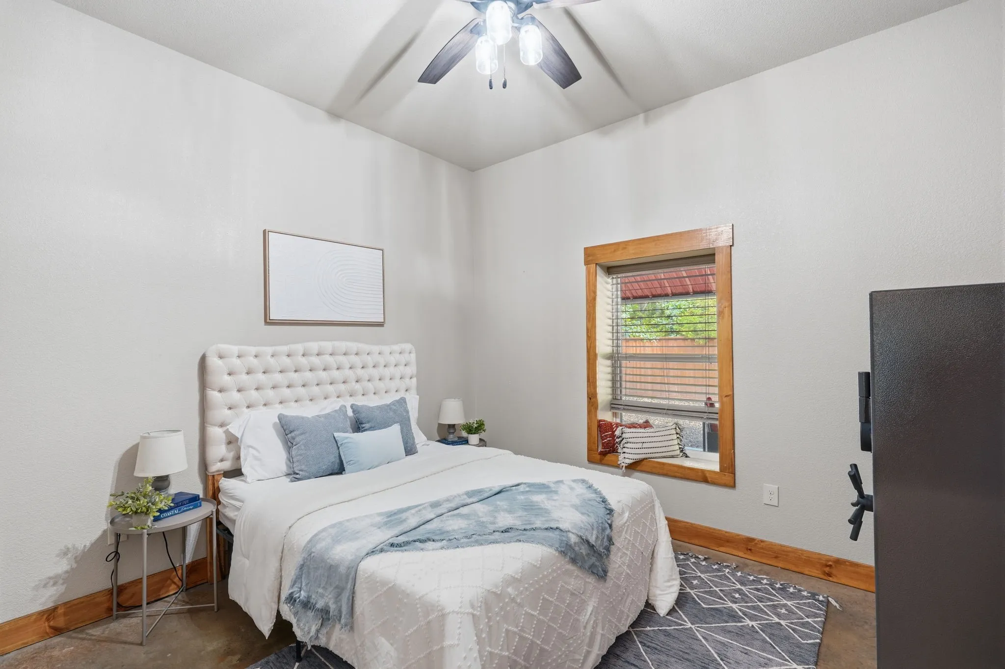 High ceilings with a ceiling fan fixture, a window with wood trim, and wood-finish baseboards