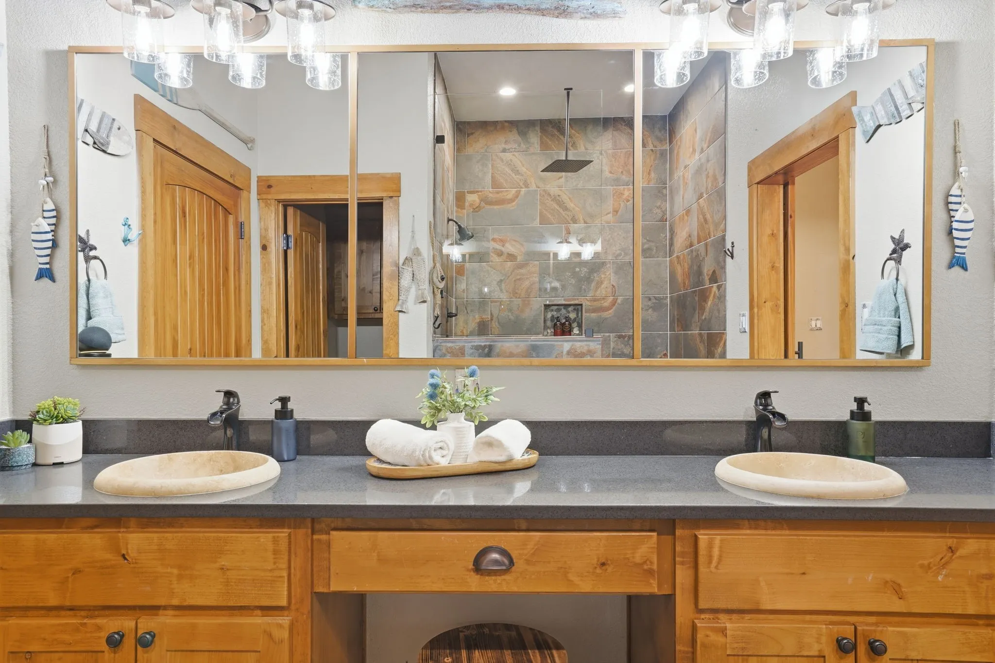 Dual vessel sinks set into a gray countertop, complemented by natural wood-finish cabinetry