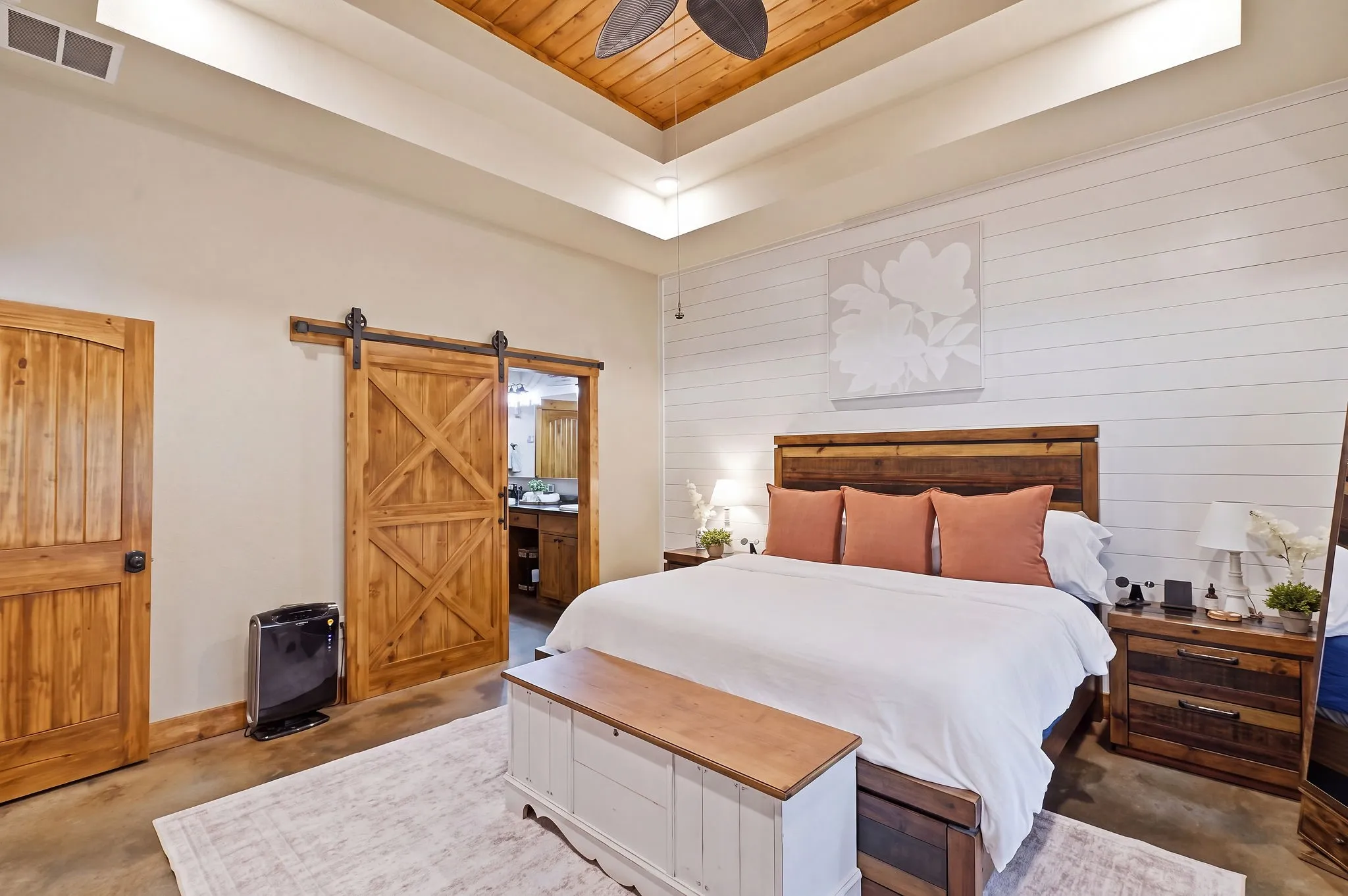 Tray ceiling with wood-finish paneling, white shiplap accent wall, wood-finish flooring, and a wood-finish barn door