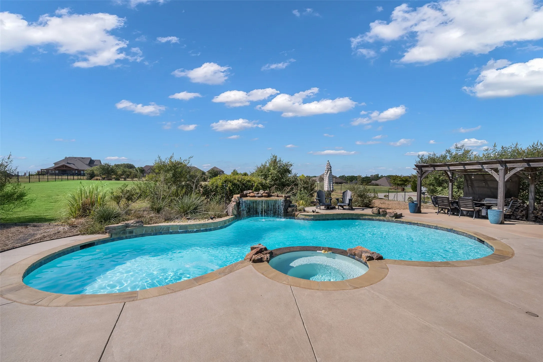Freeform swimming pool with integrated spa and rock waterfall feature