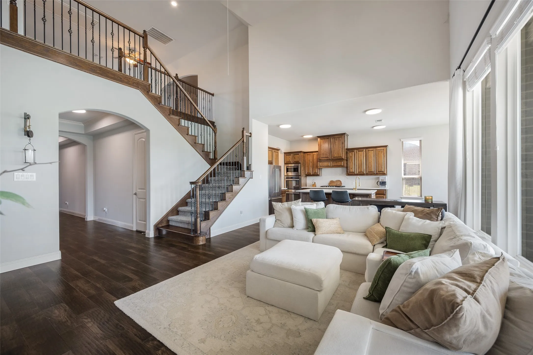 Two-story architectural design with high ceilings, wood-finish flooring, and a grand staircase featuring iron balusters