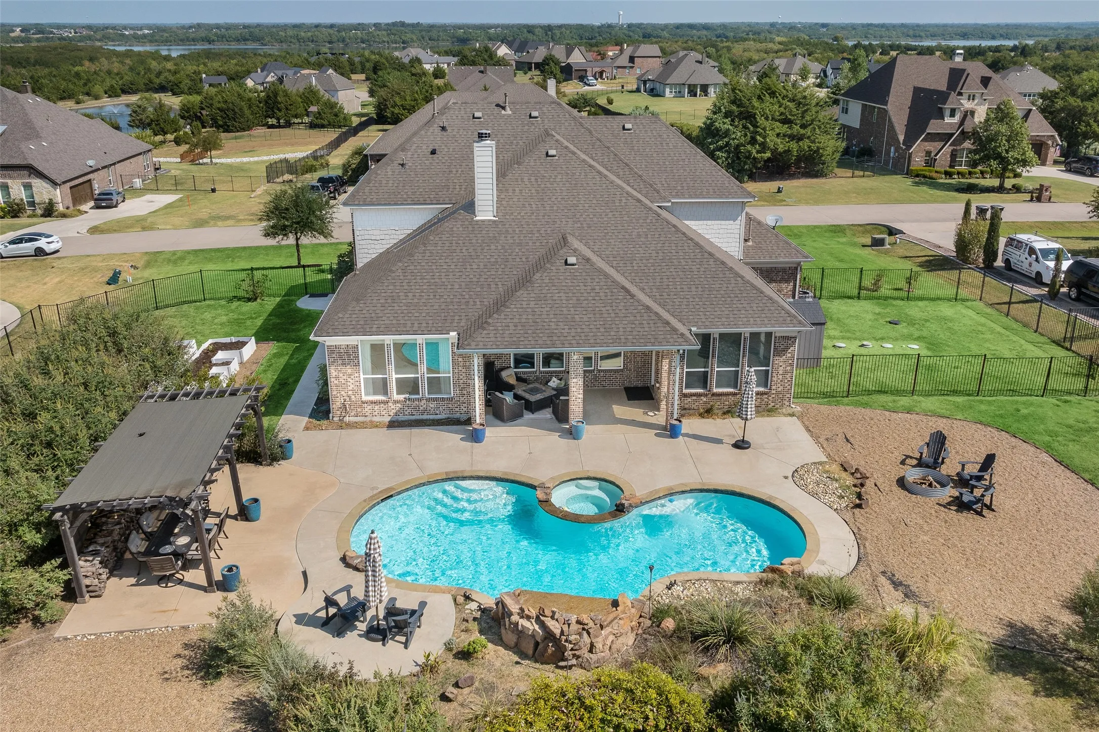 Expansive backyard featuring a freeform swimming pool with integrated spa, a dedicated fire pit area, a covered patio, and a pergola structure